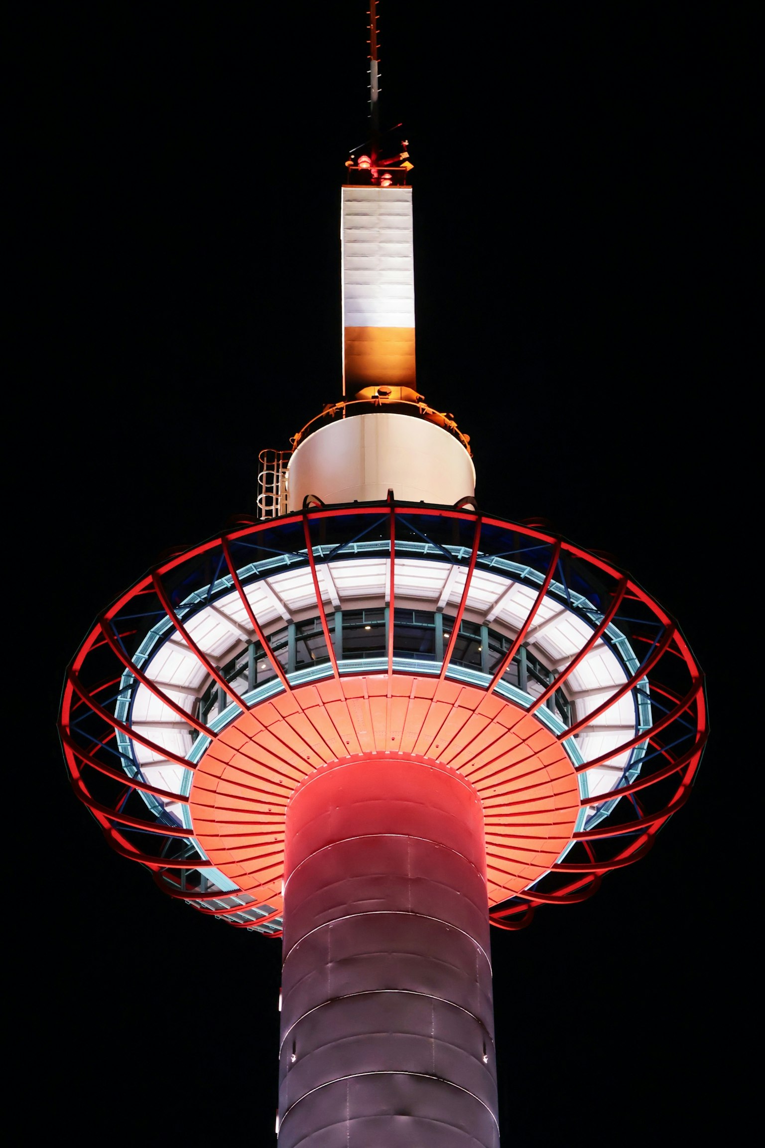 Illuminated tower at night featuring red and white lights