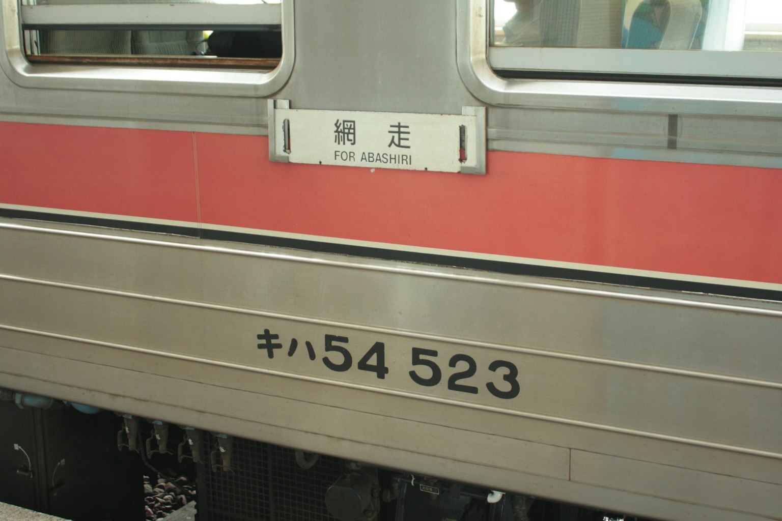 列车侧面带有红色条纹和车辆编号Kiha 523
