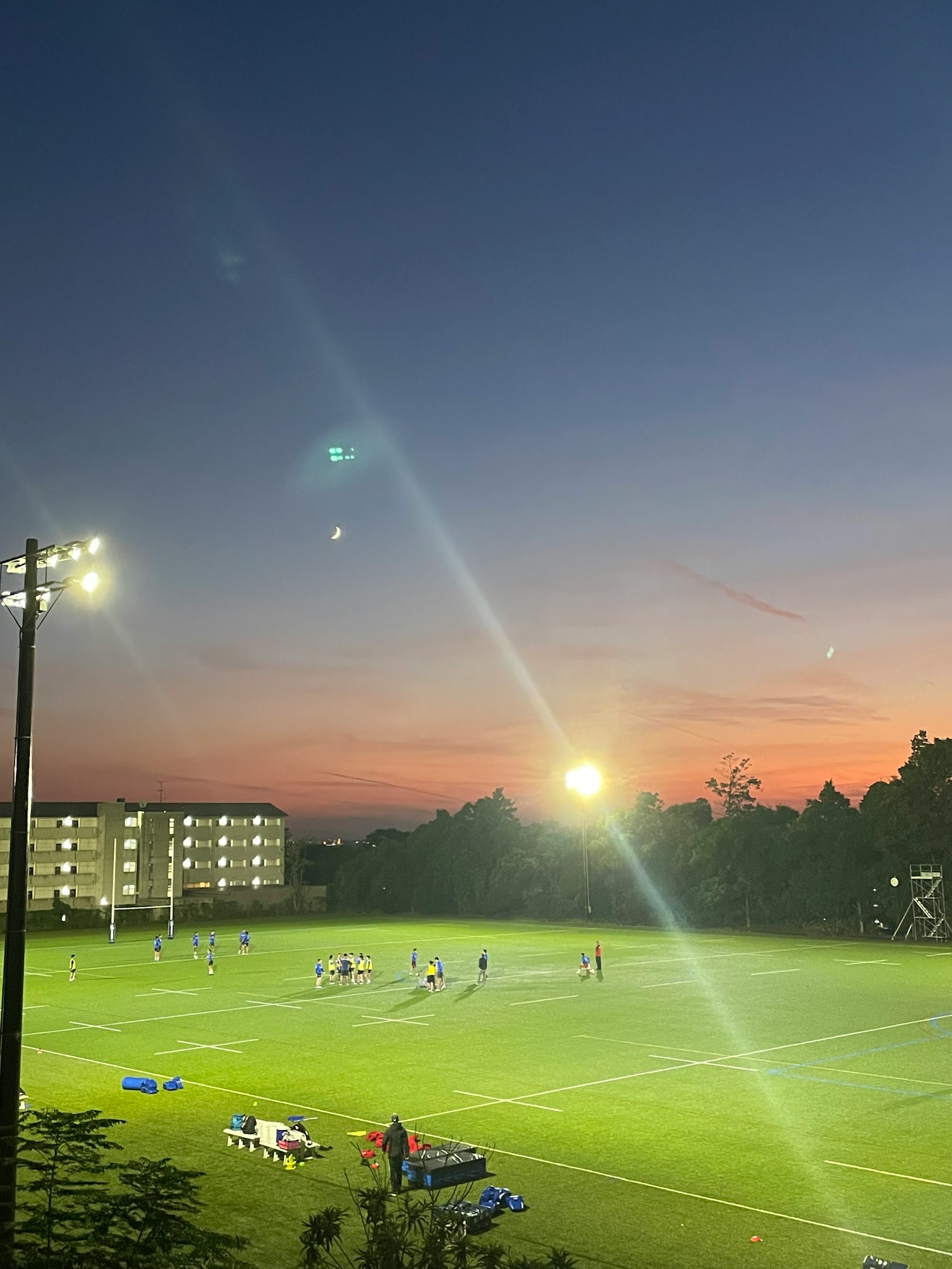 Joueurs s'entraînant sur un terrain de sport au crépuscule avec des lumières vives