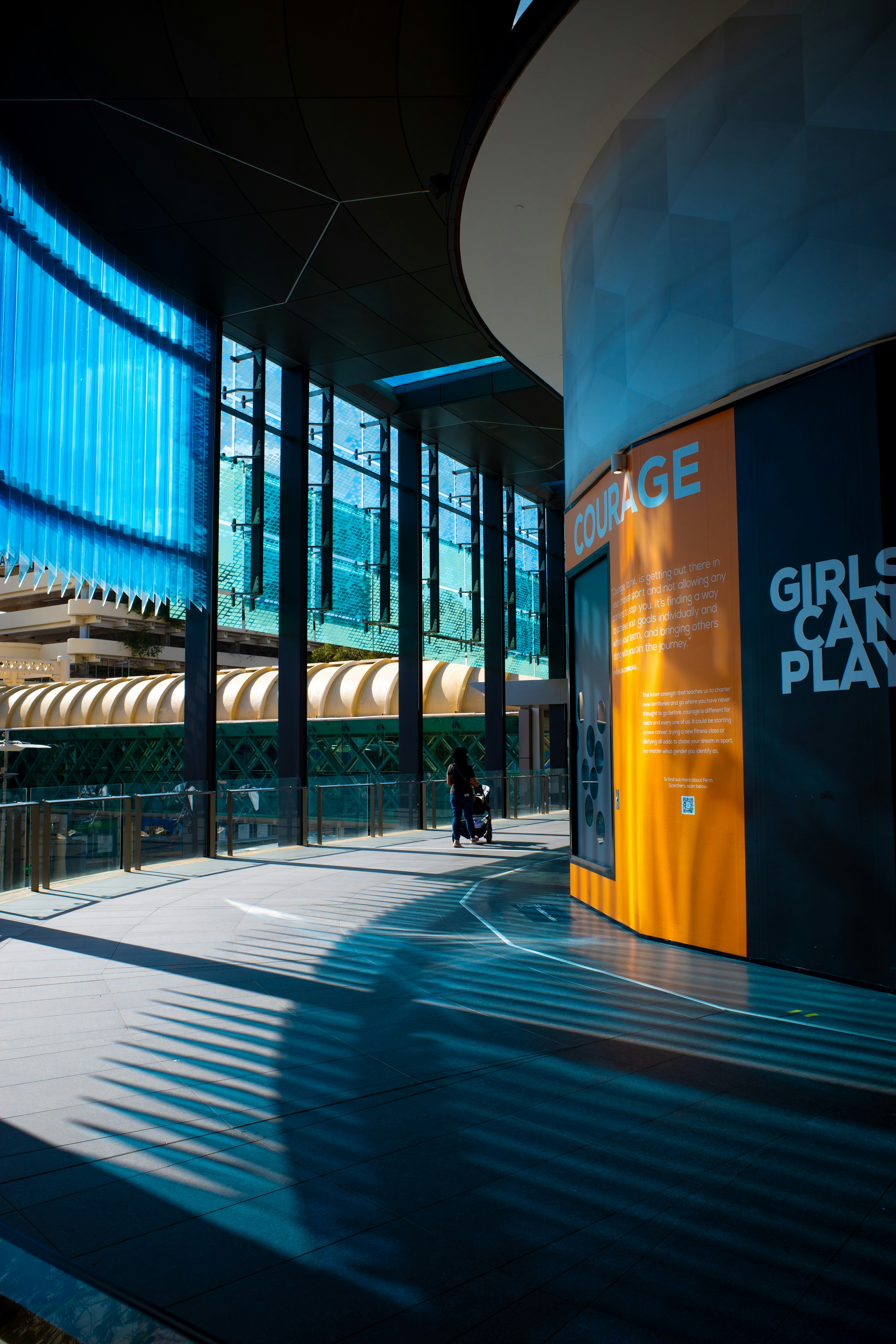 glass-walled corridor with exhibition banners in a modern indoor space