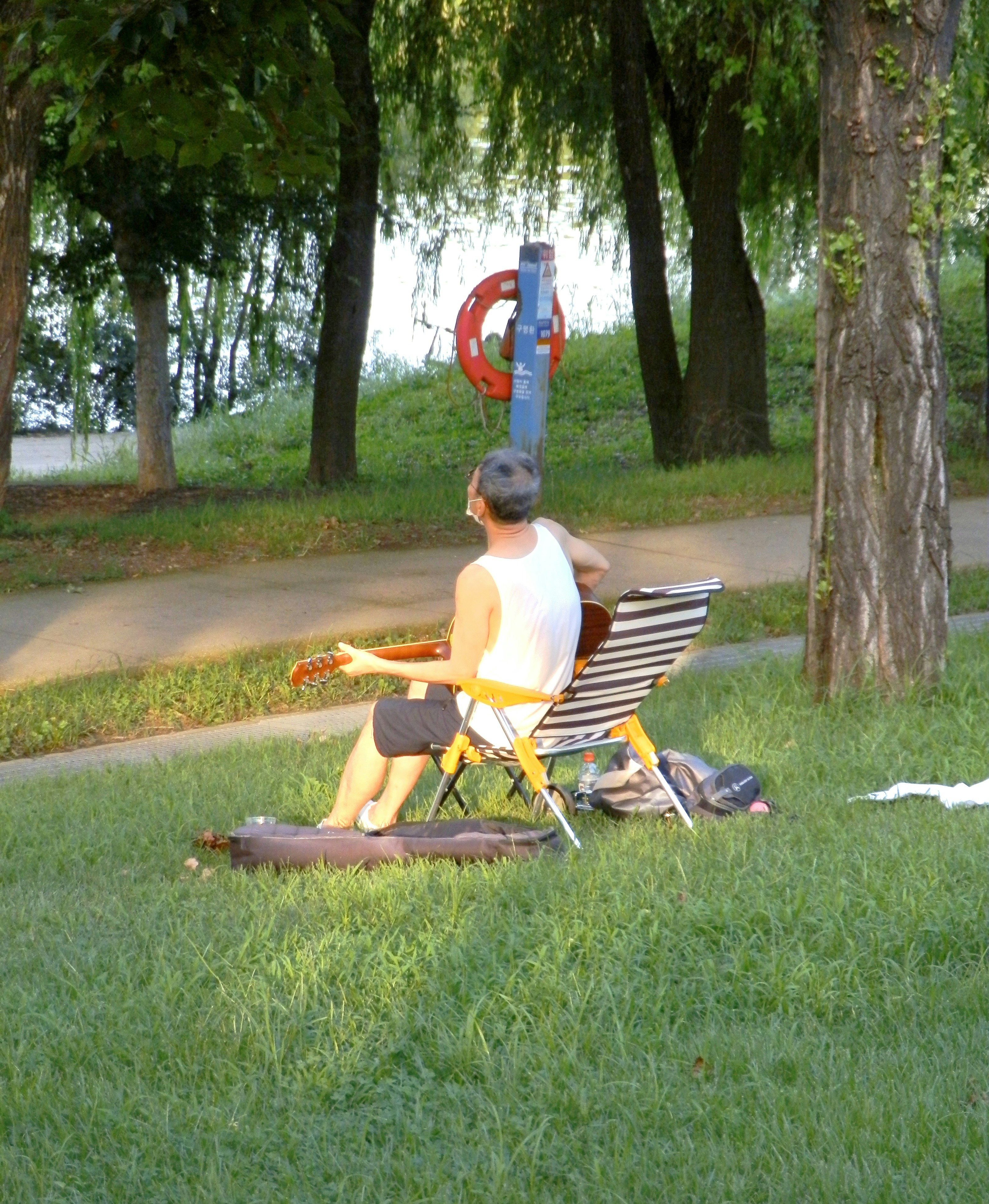 公園の芝生でギターを弾くシニアの男性