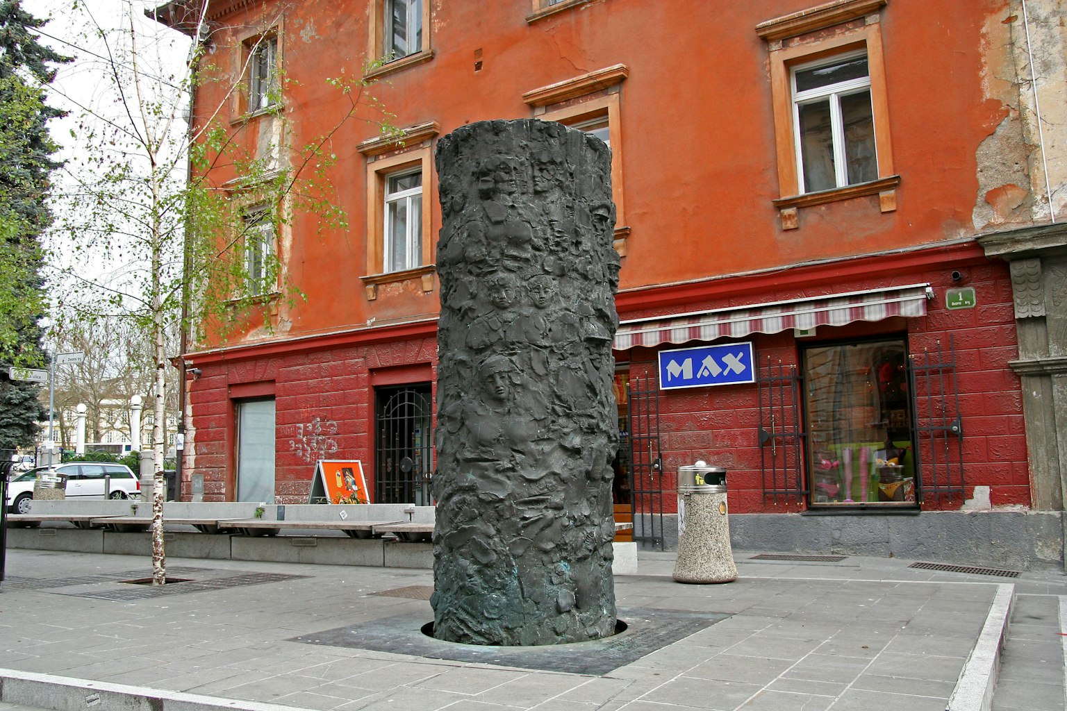 Una colonna scultorea nera di fronte a un edificio con pareti rosse