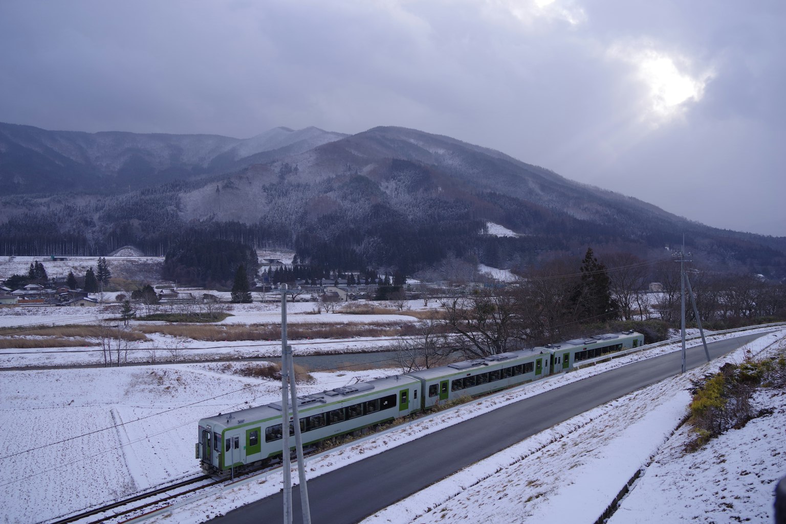 Train vert circulant à travers un paysage enneigé avec des montagnes