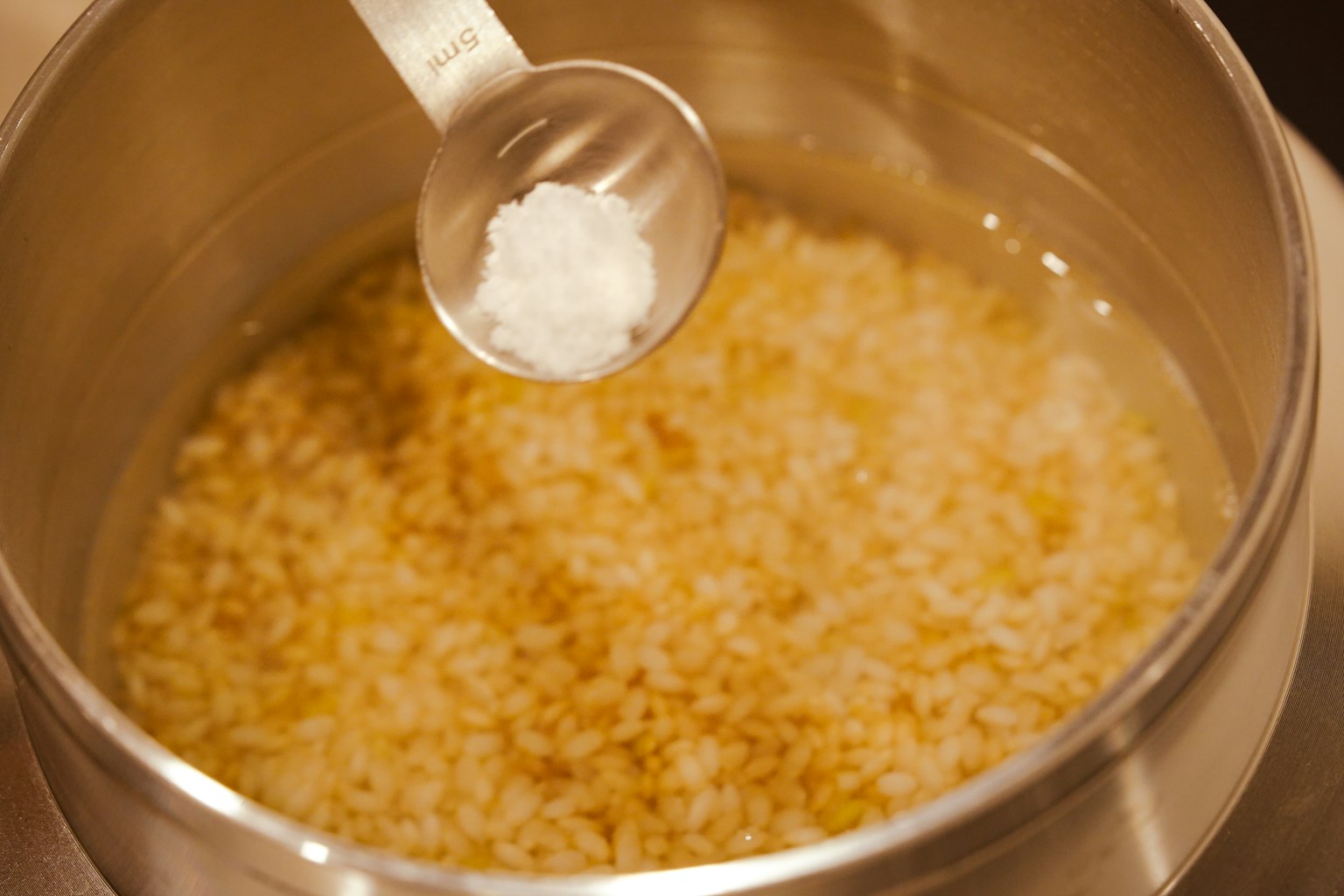 Ajout de sel dans une casserole de riz en cuisson
