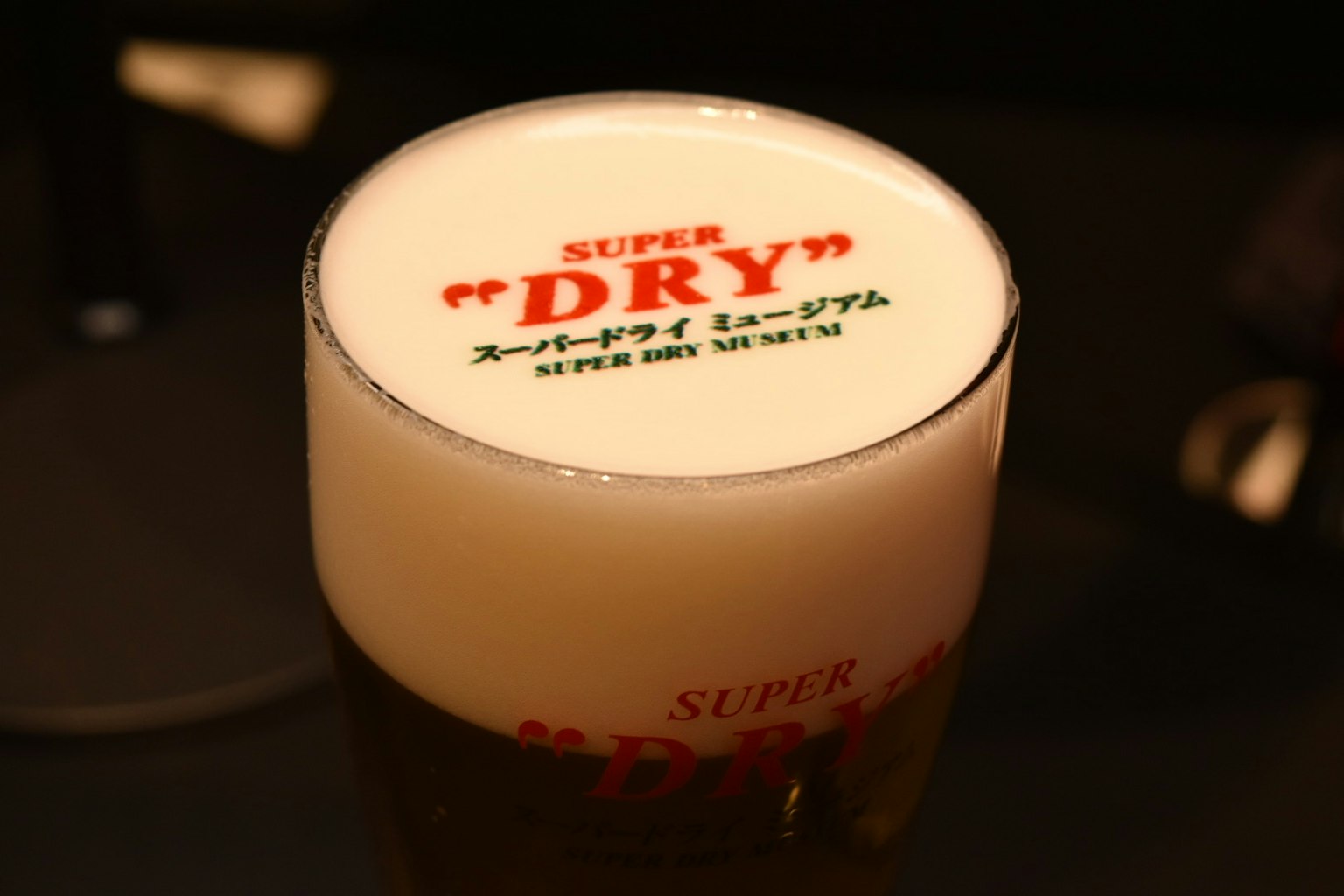 A glass of beer with foam topped by the text SUPER DRY