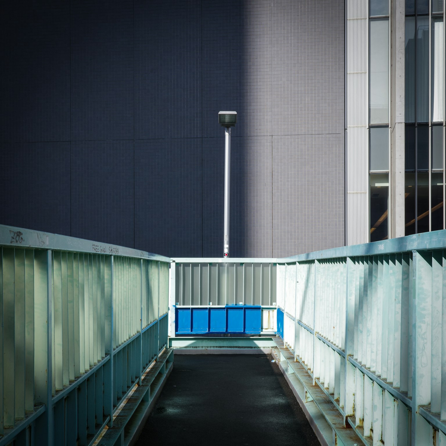 一个现代的步道，配有蓝色的护栏和街灯，背景是建筑物