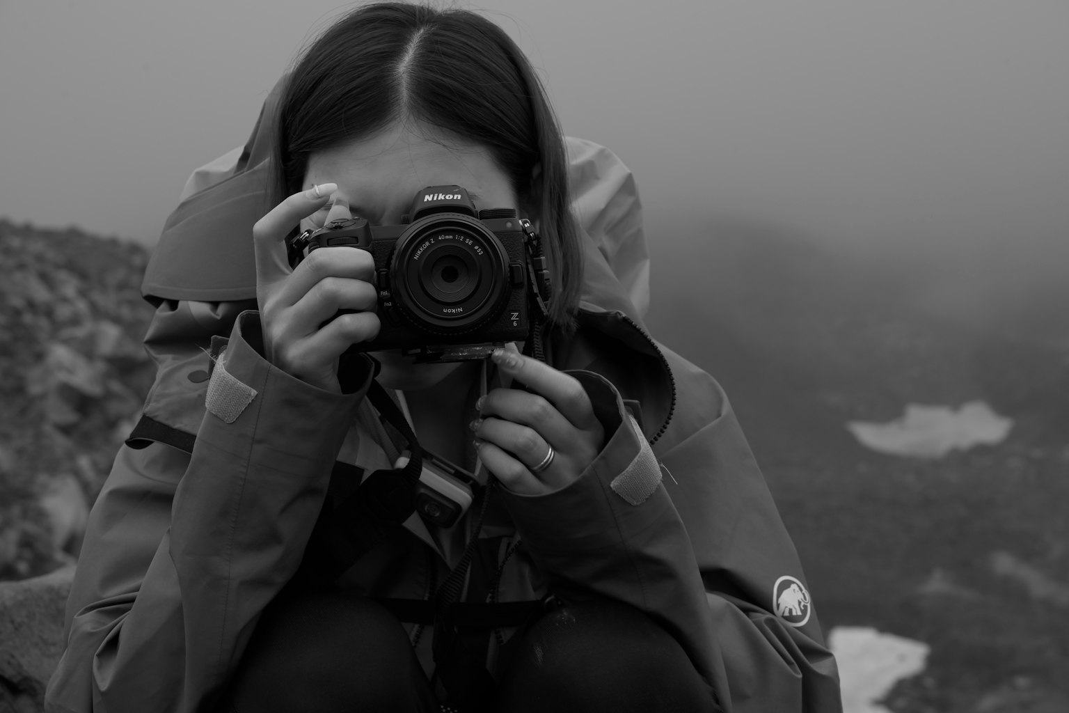 Foto en blanco y negro de una mujer sosteniendo una cámara en la niebla