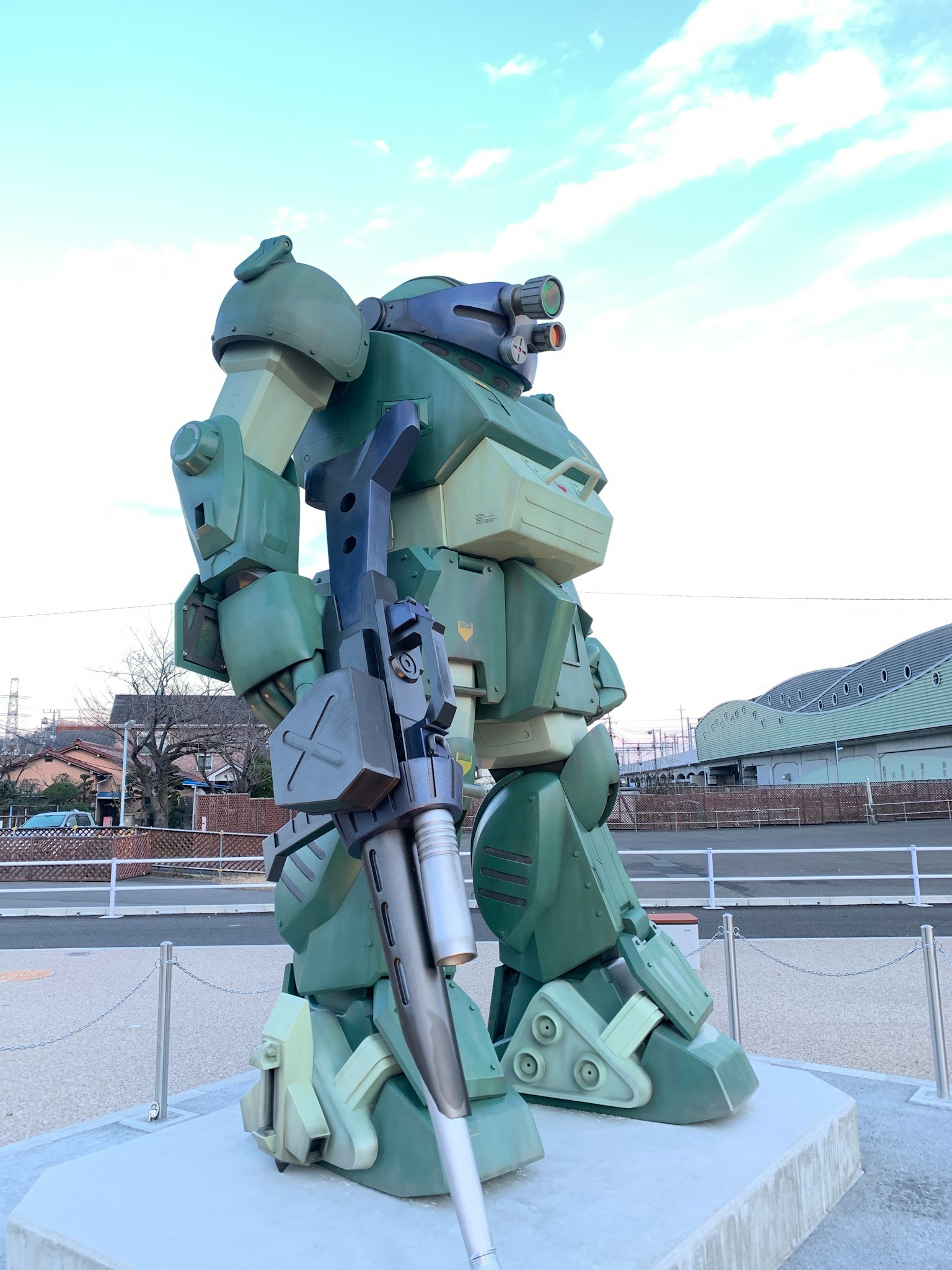 Estatua de robot verde sosteniendo un arma de pie al aire libre