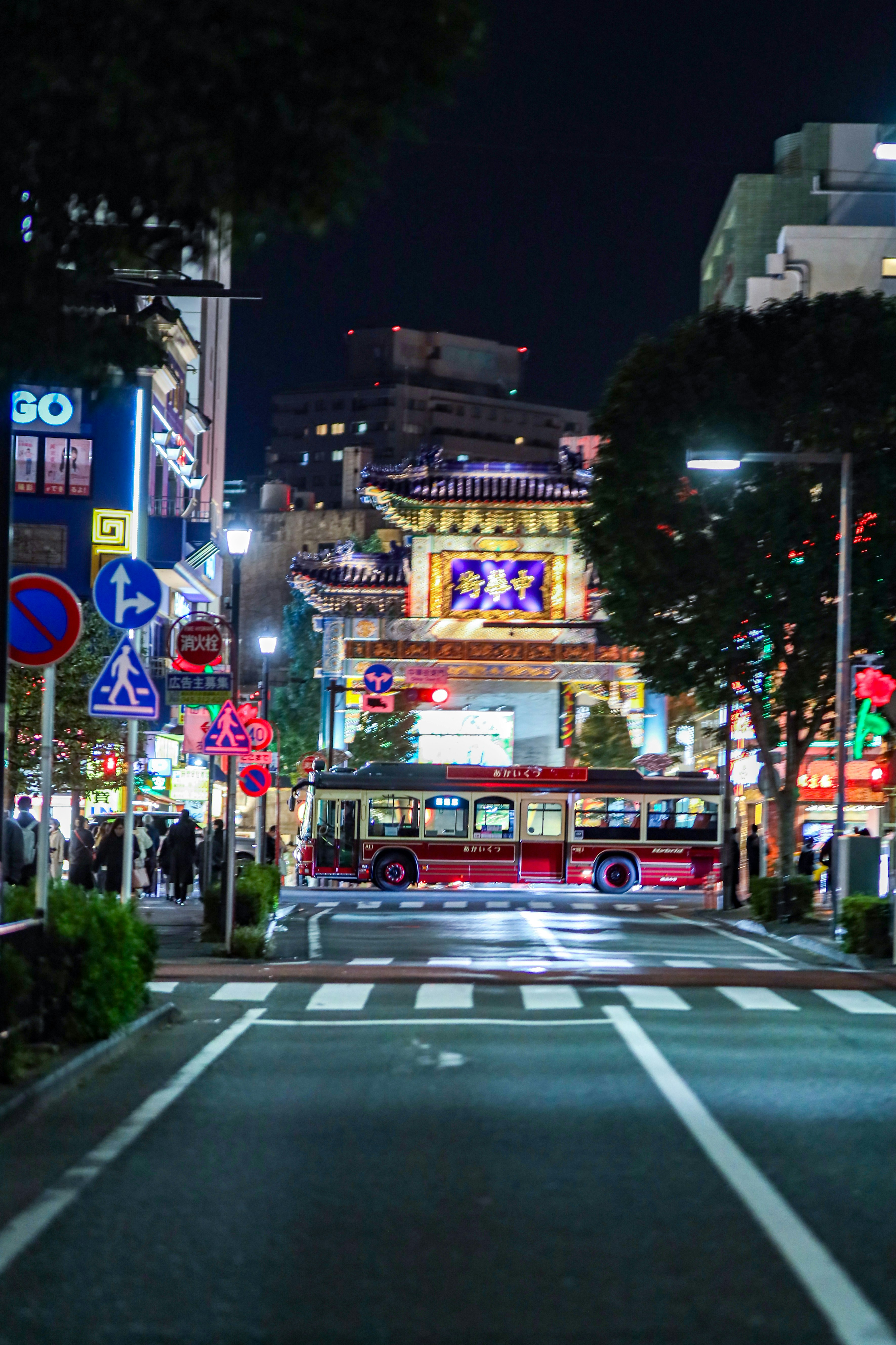 夜の街角で走る路線バスとネオン看板のある交差点