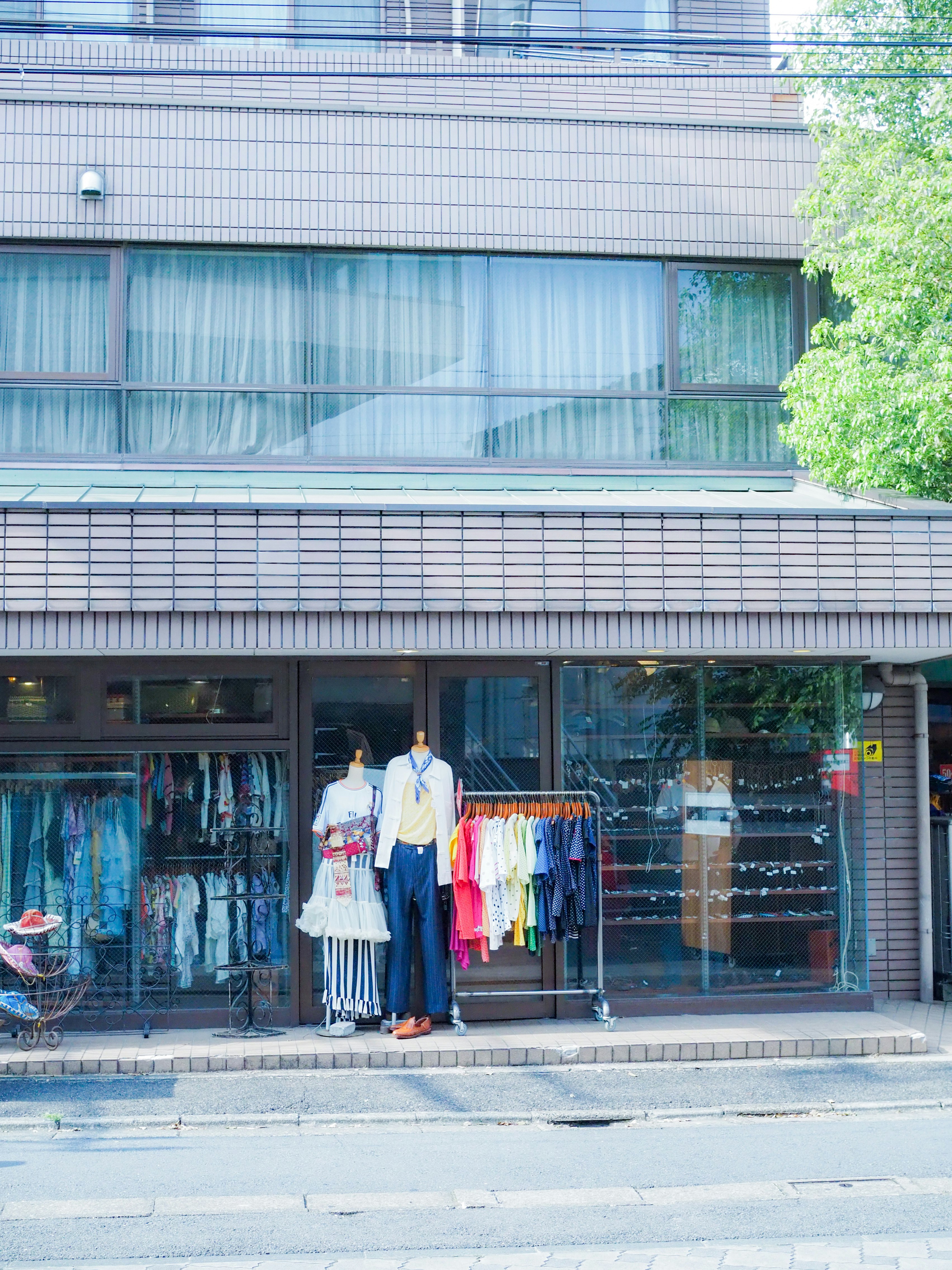 ガラス張りの店舗前に並ぶ衣類とマネキン