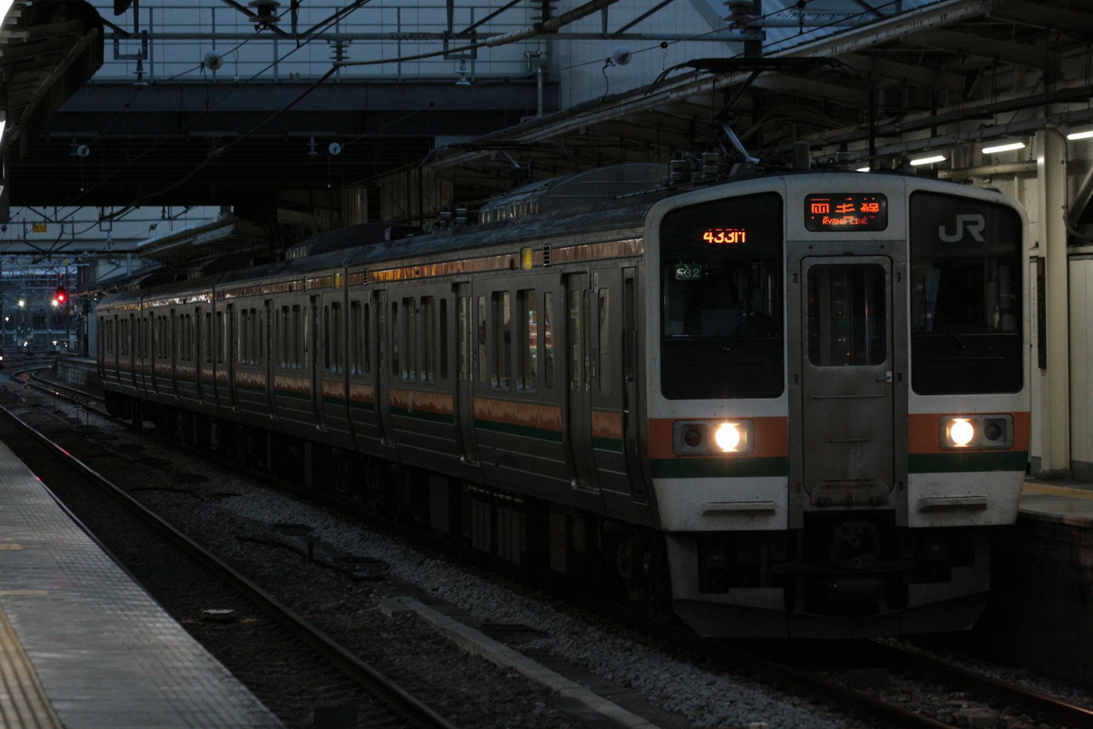 JR列車停靠在昏暗的車站，燈亮著