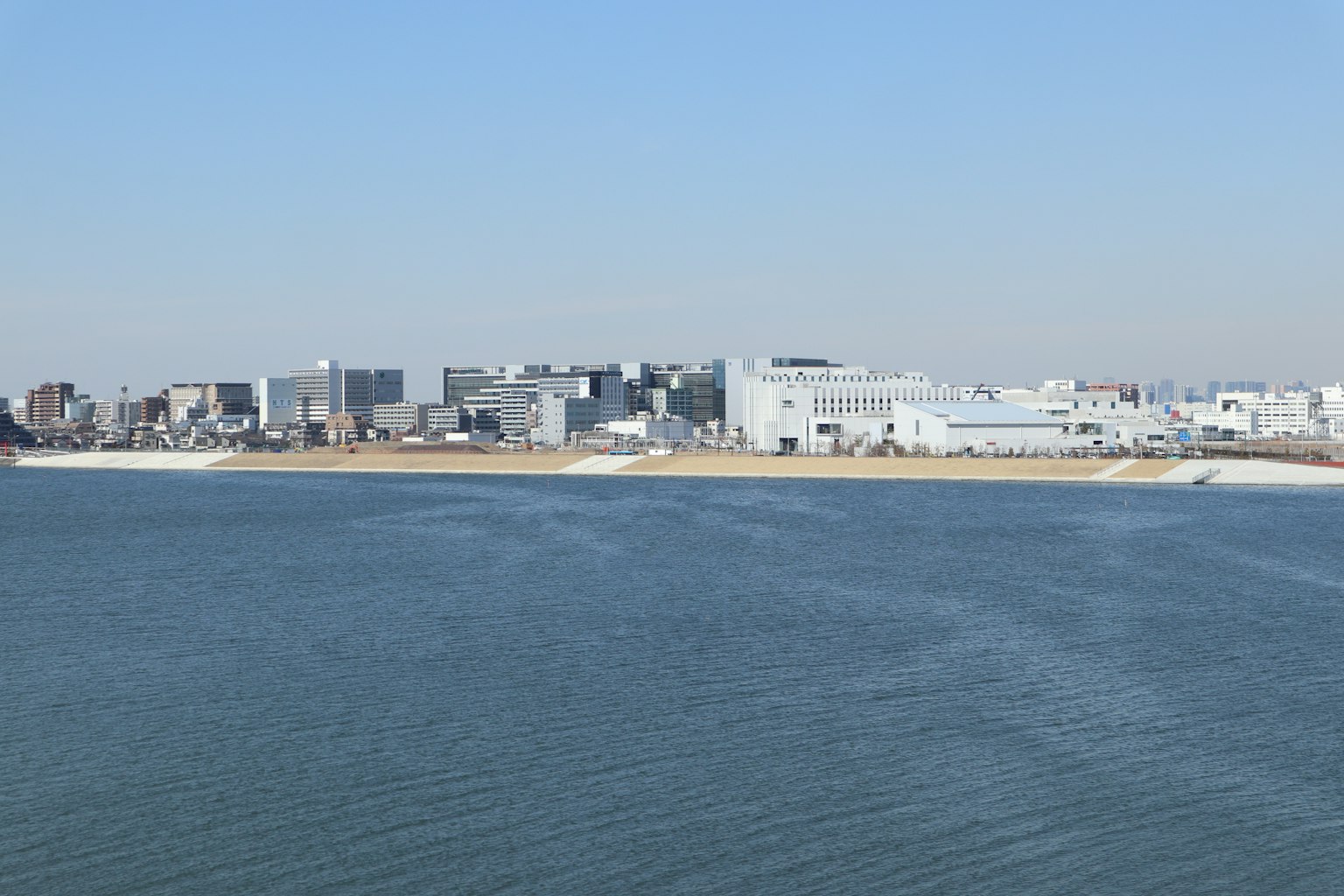 Stadtansicht mit modernen Gebäuden am Wasser unter klarem blauen Himmel
