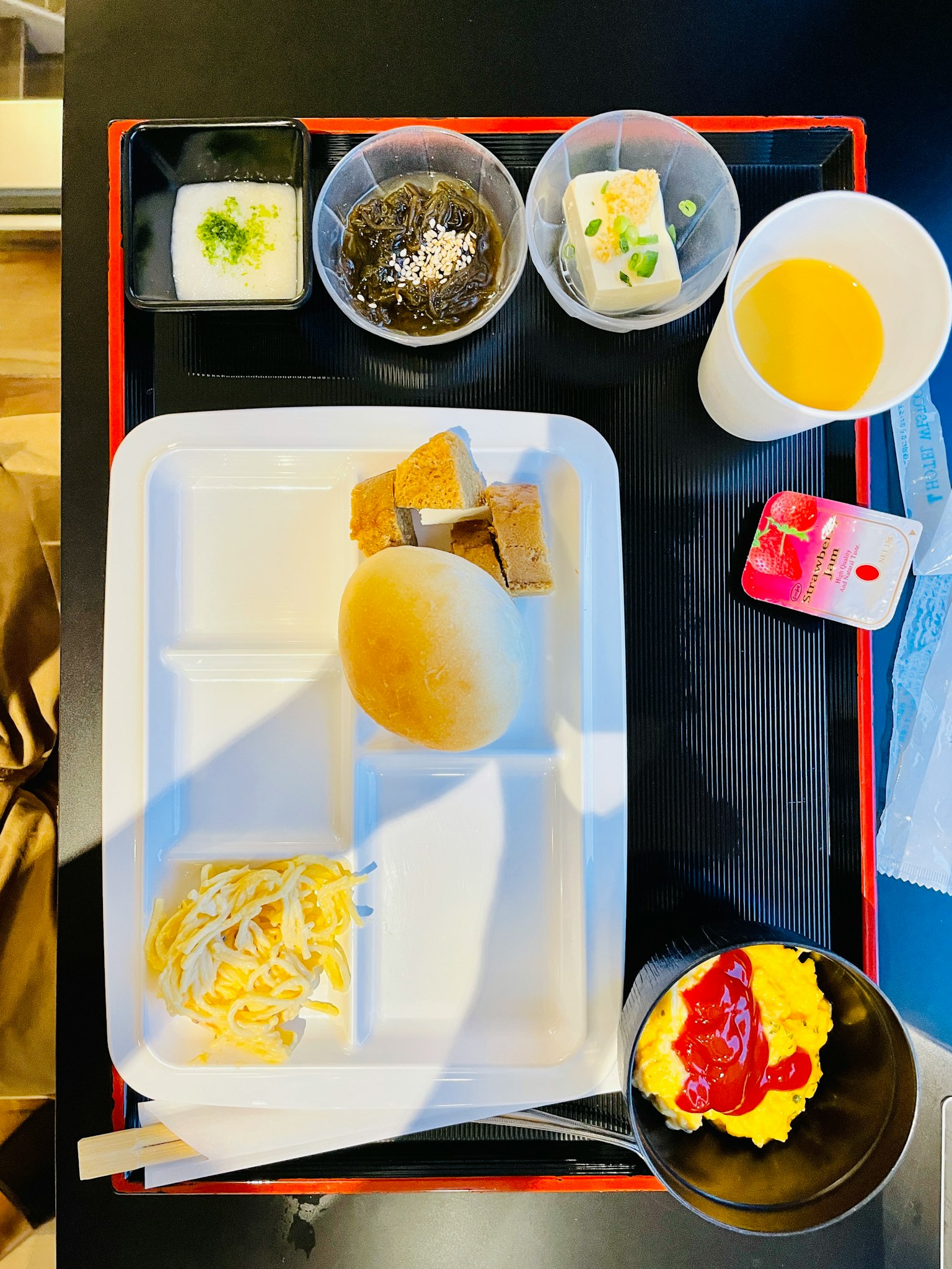 Breakfast tray featuring egg dish, bread, desserts, and beverages