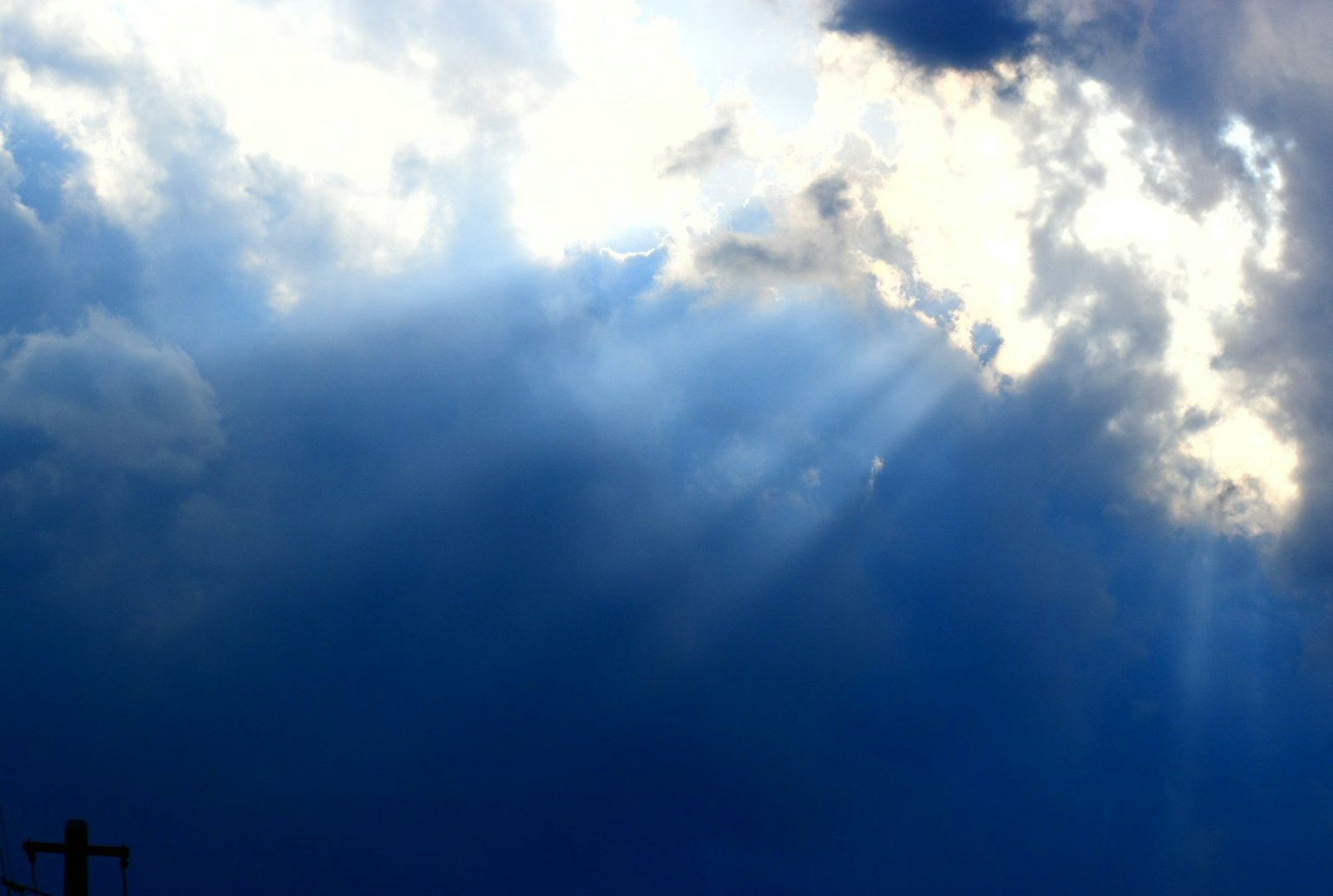 Blauer Himmel mit Lichtstrahlen, die durch die Wolken scheinen