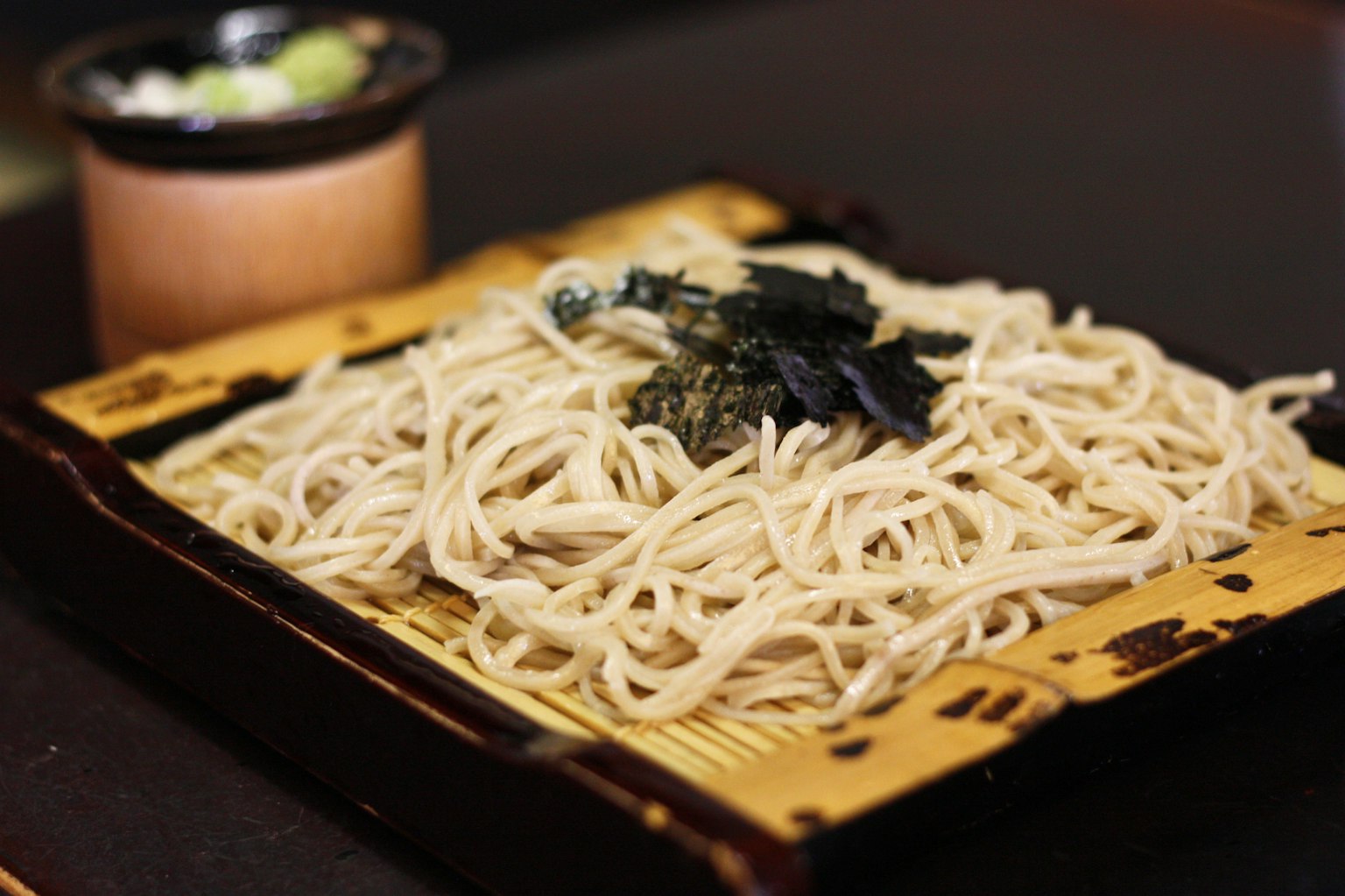 蕎麥麵放在竹盤上，旁邊有一個小碗裝著芥末
