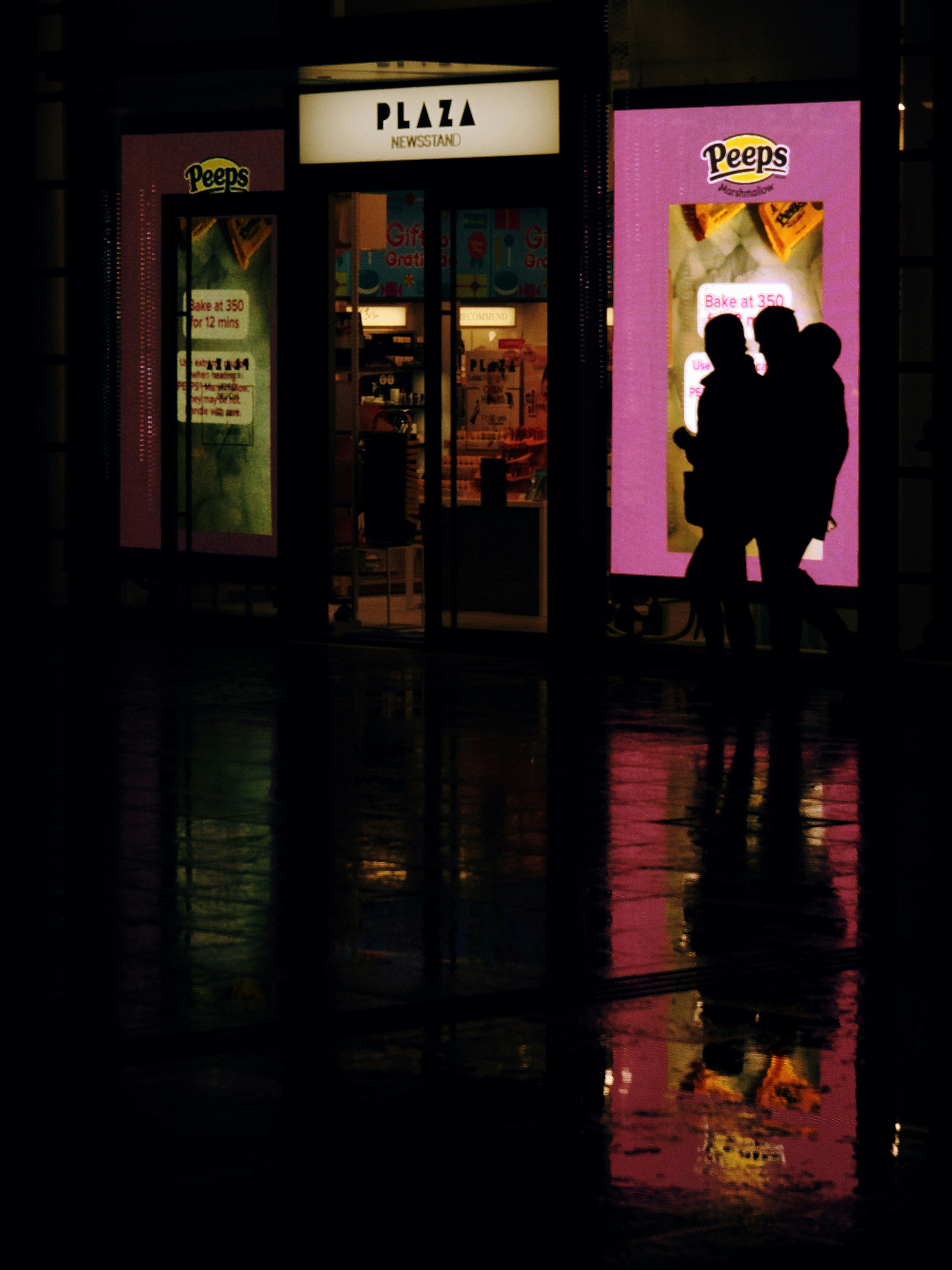 雨の夜の街角で反射するネオン看板と人影