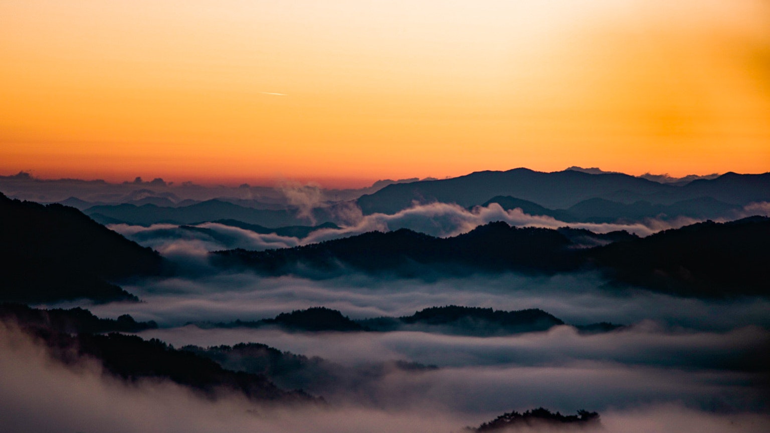 Bellissimo paesaggio al tramonto con montagne avvolte nella nebbia