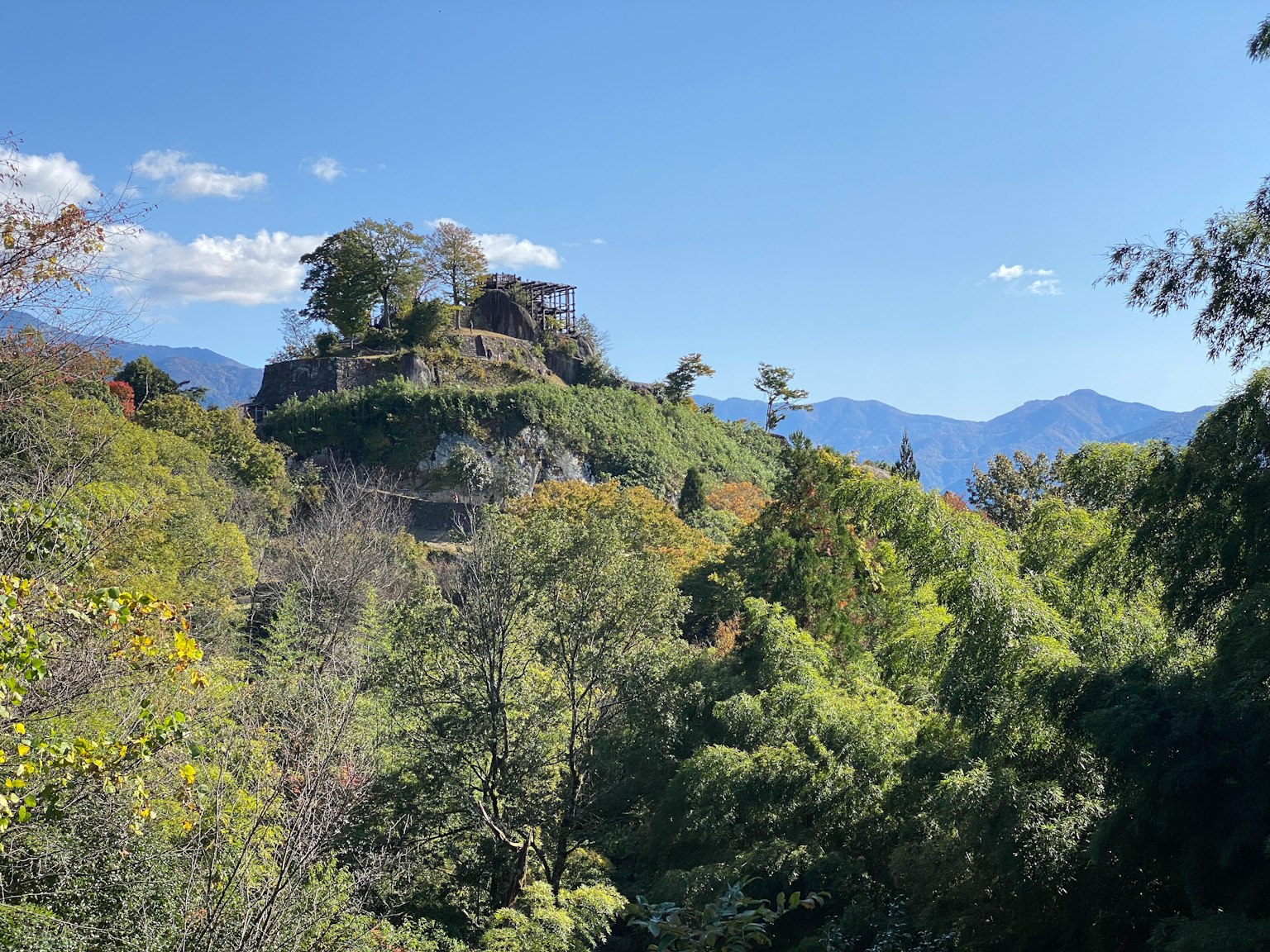 Une ruine de château ancien sur une colline verdoyante entourée d'arbres et d'un ciel bleu clair