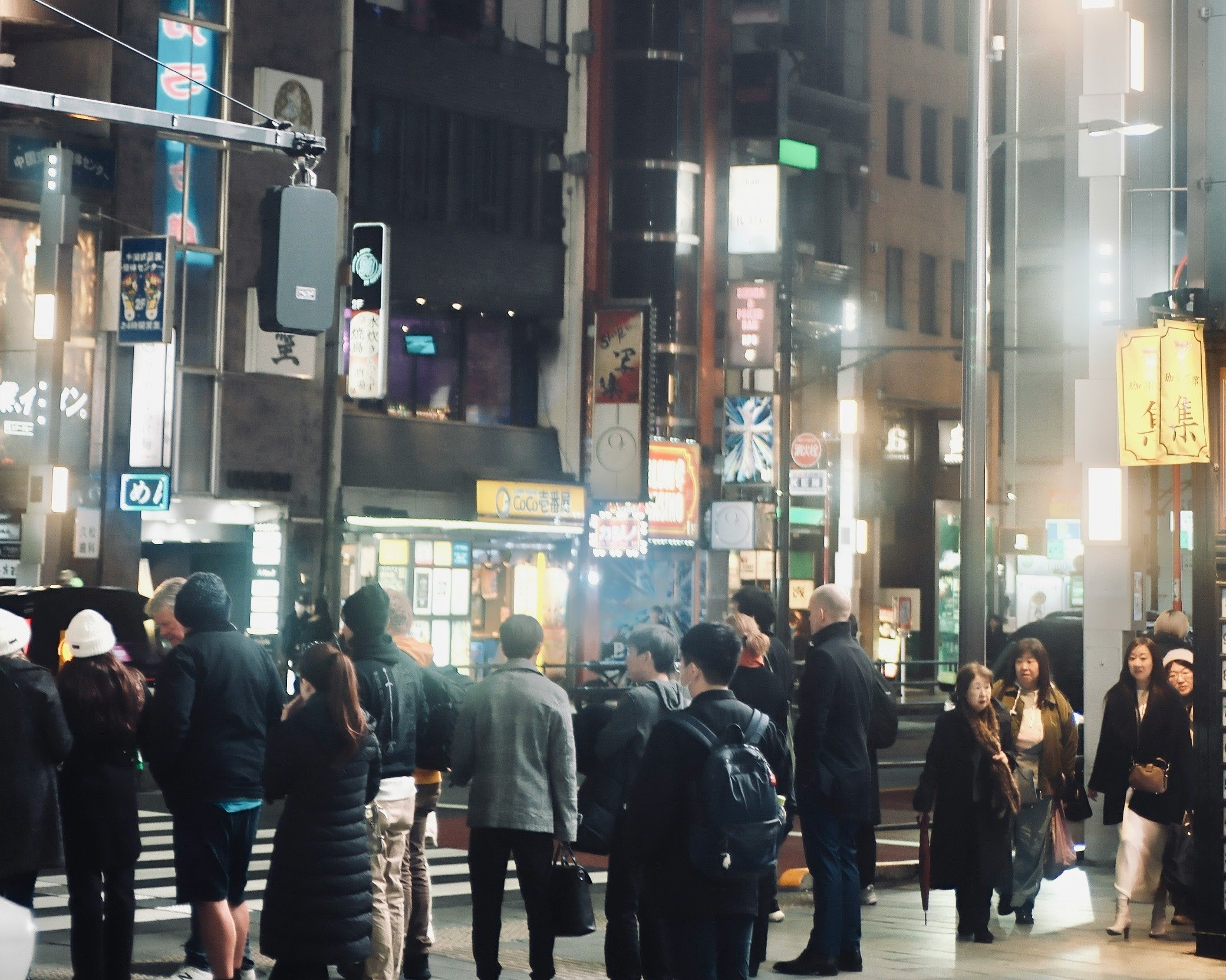 夜の繁華街を歩く人々の行列が交差する街角