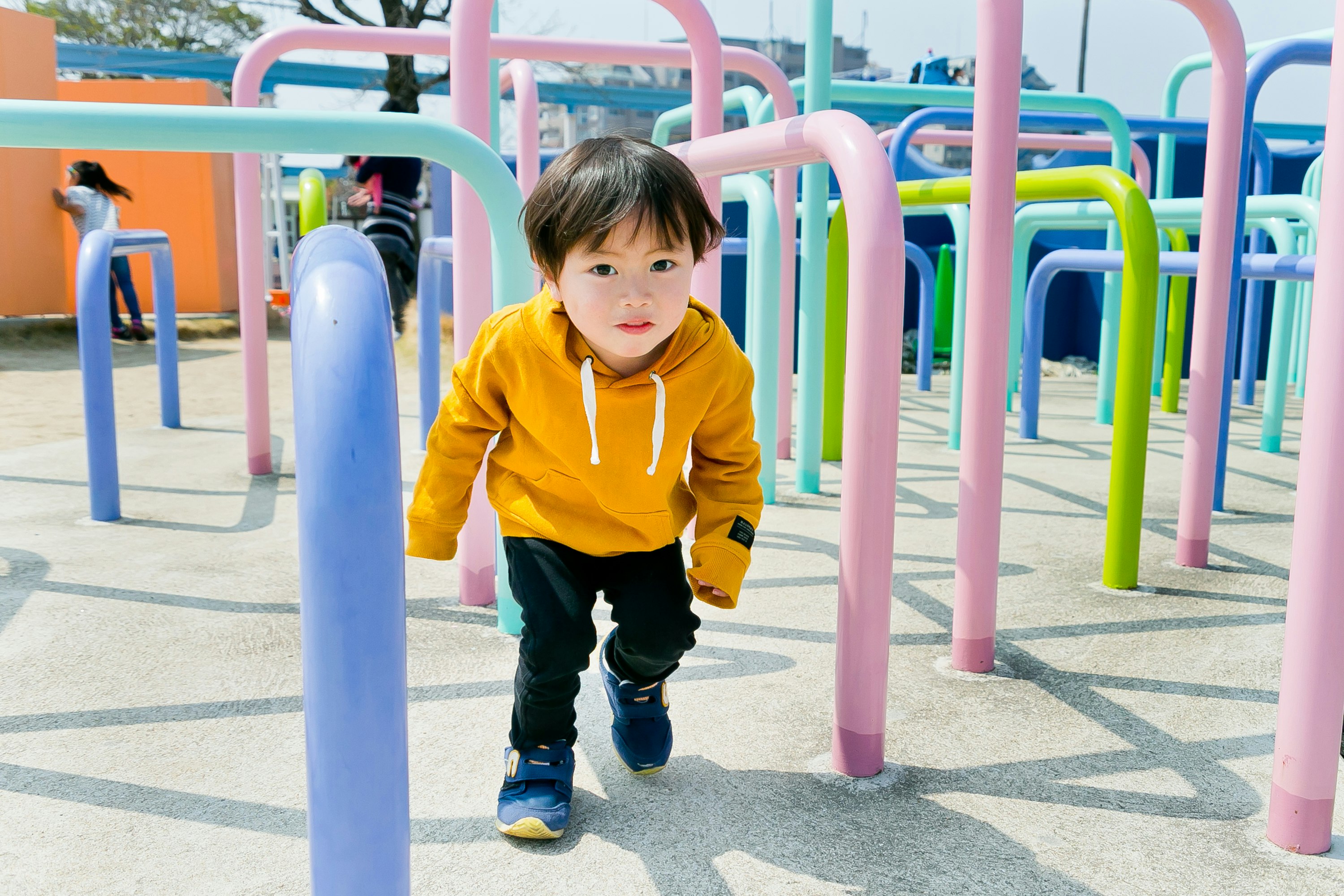 toddler walking outdoors near colorful playground equipment