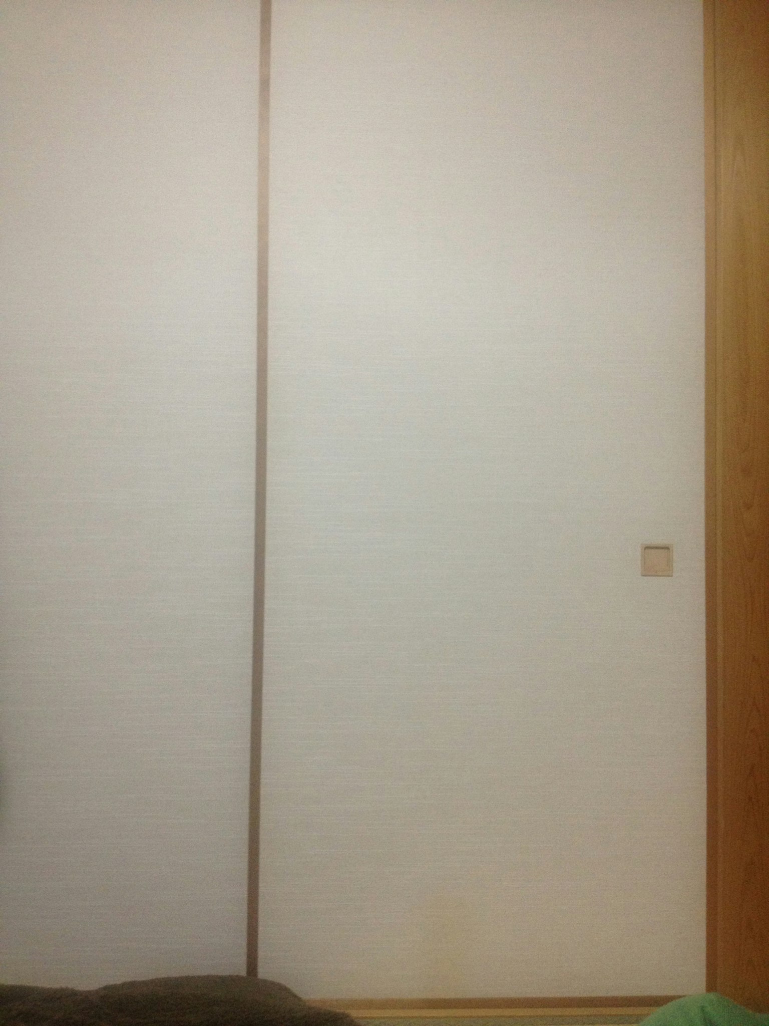 A section of a room featuring a white wall and wooden frame