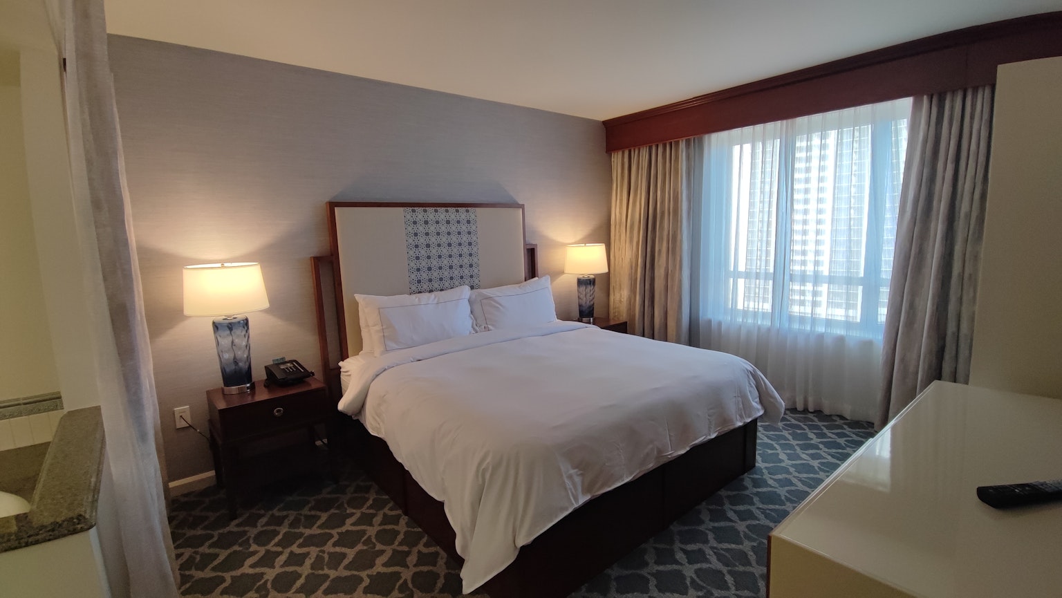 Modern hotel room featuring a large bed and bright windows