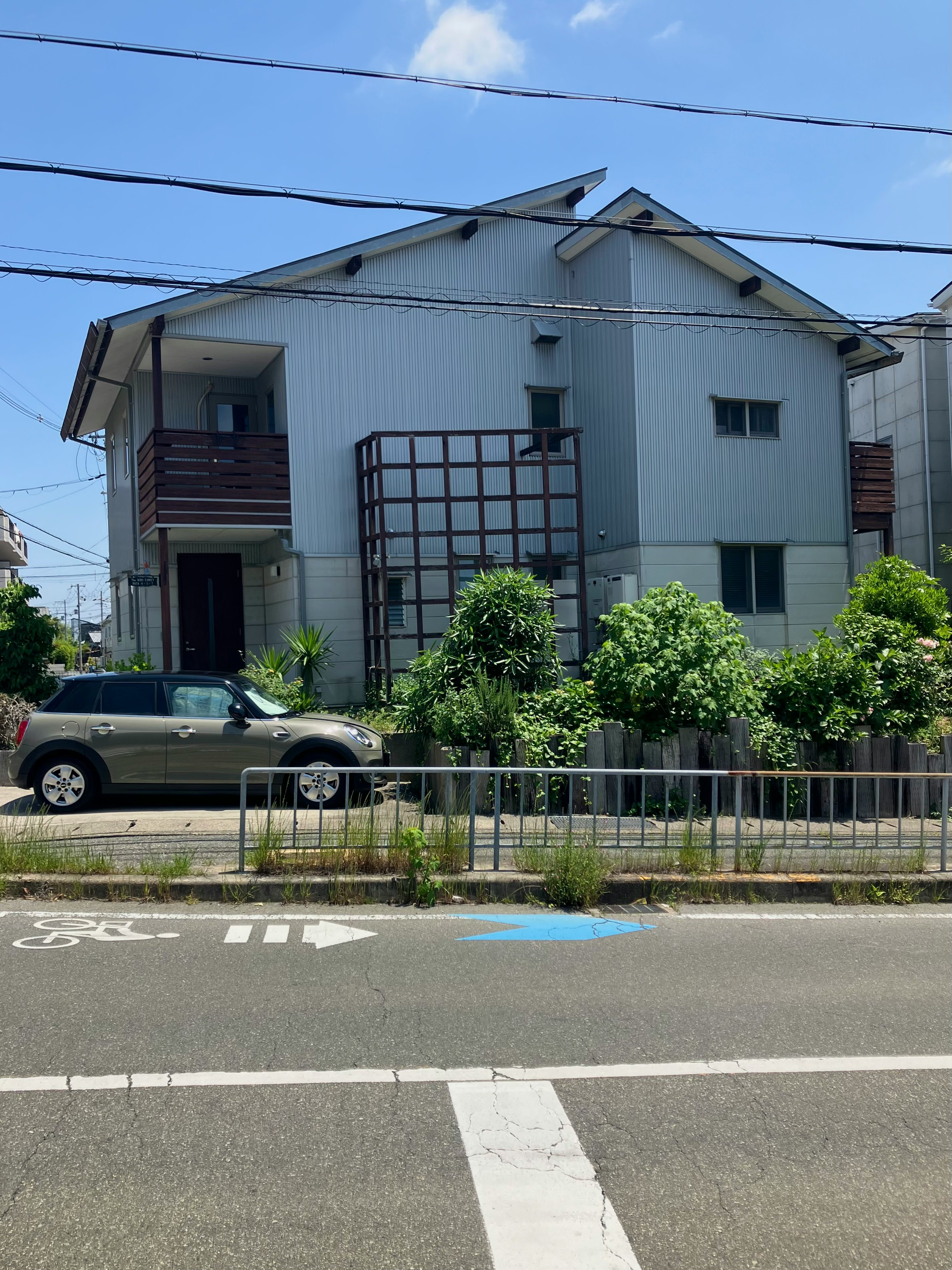 weiße freistehende Villa und Zaun an einer Straßenecke unter blauem Himmel