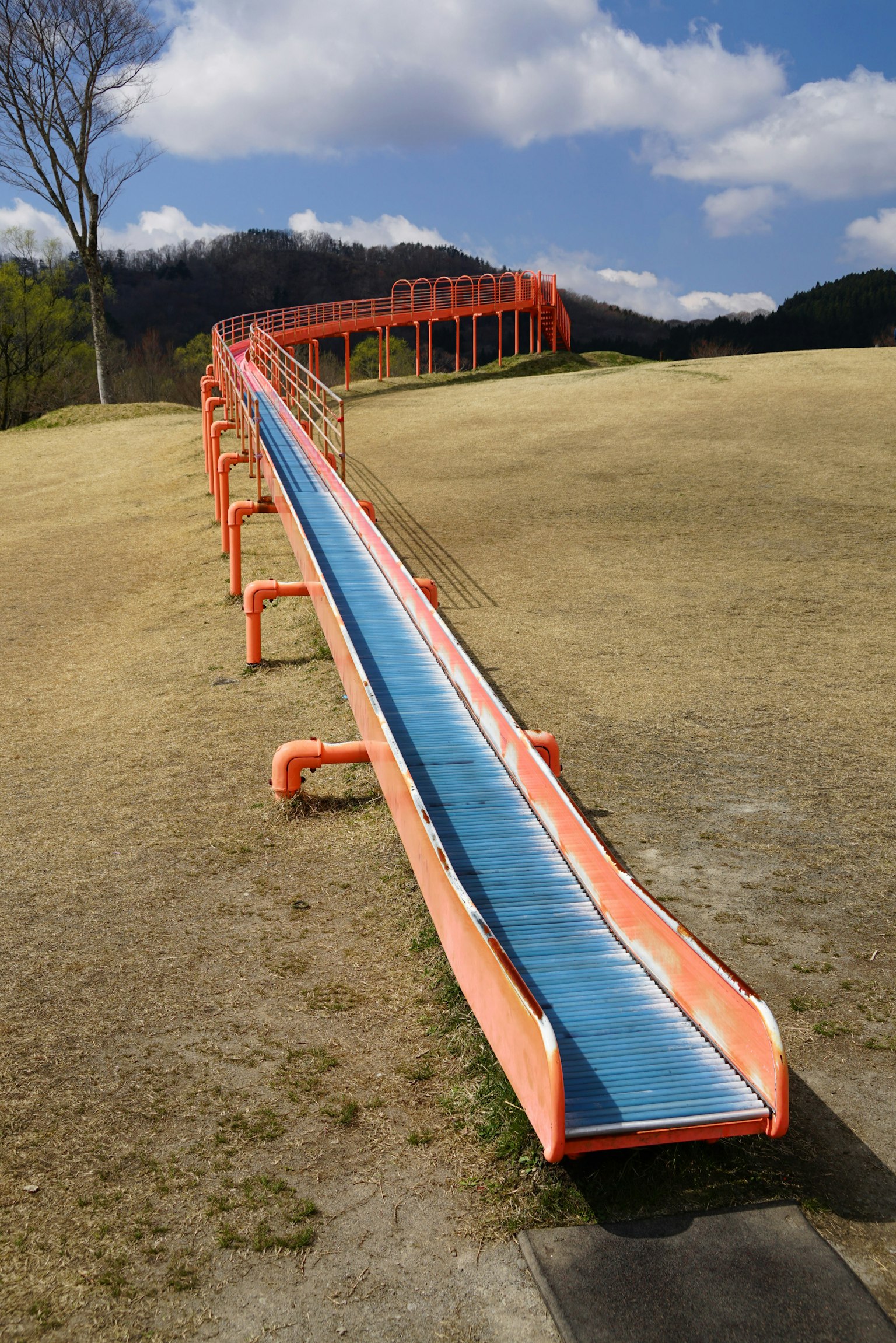 Larga resbaladilla naranja con superficie azul en un parque