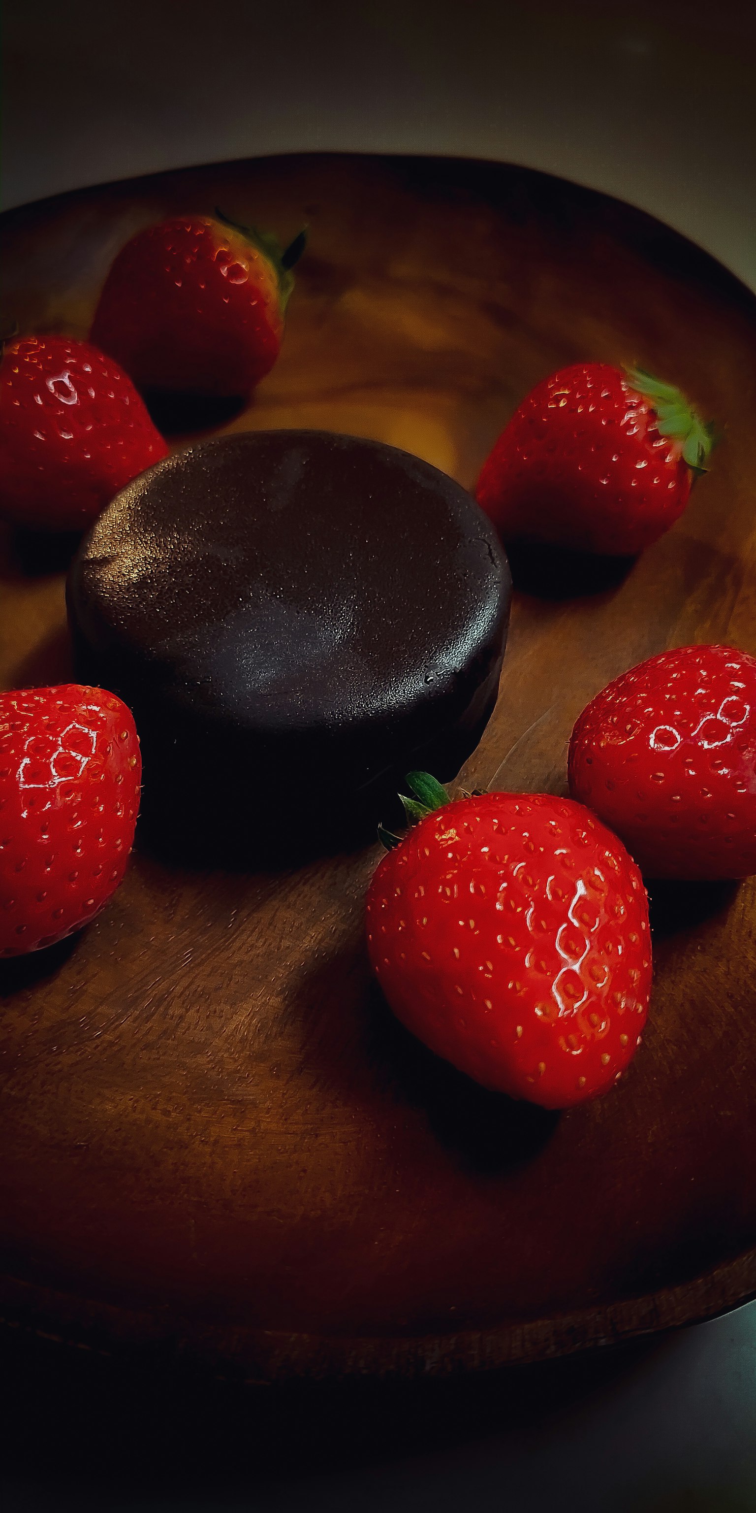 A dark chocolate cake surrounded by fresh strawberries