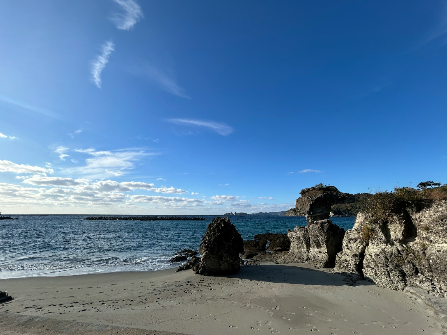 Vista panoramica di una spiaggia con cielo blu e mare calmo caratterizzata da rocce e sabbia