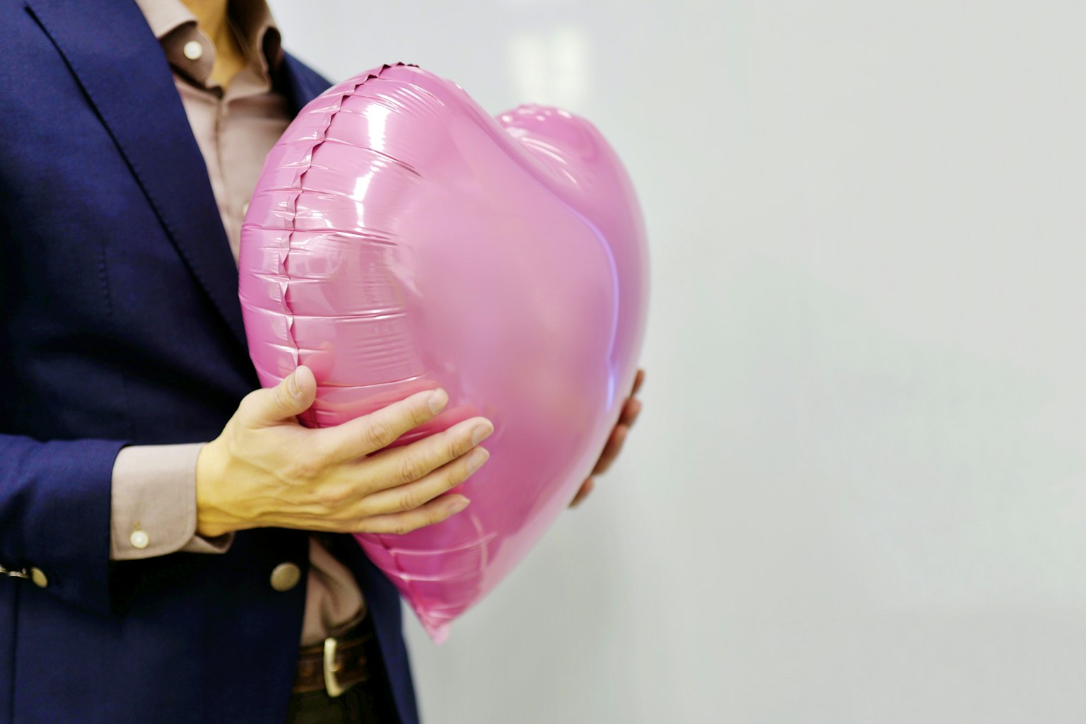 Pria memegang balon berbentuk hati berwarna pink