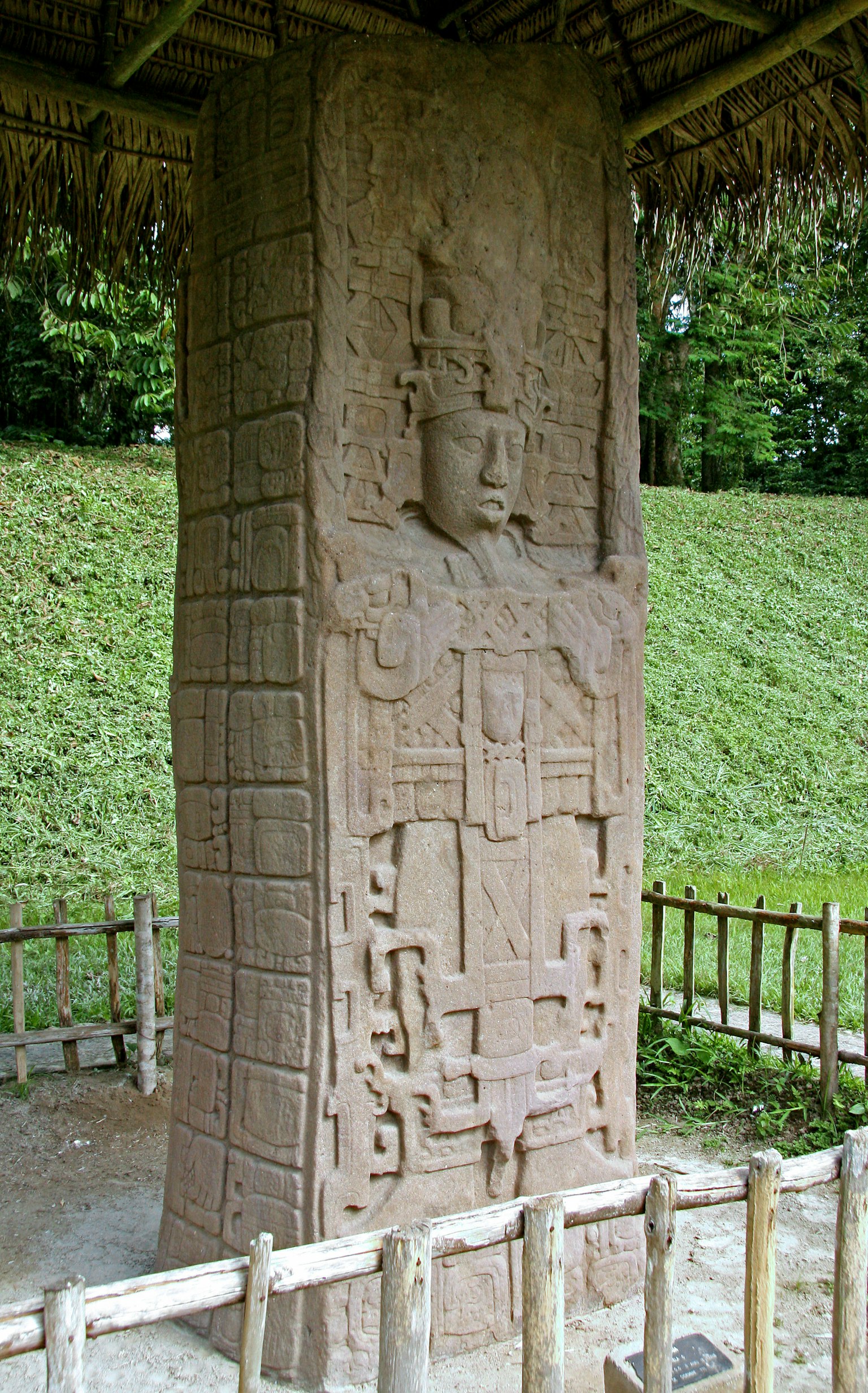 Sebuah monumen batu yang diukir dengan desain rumit berdiri di area berumput