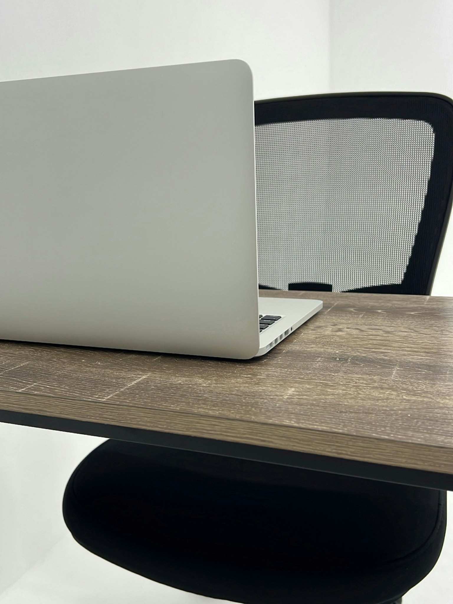Laptop màu bạc trên bàn gỗ với ghế đen