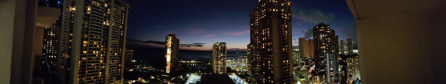 Panoramic view of skyscrapers and night sky with ocean visible