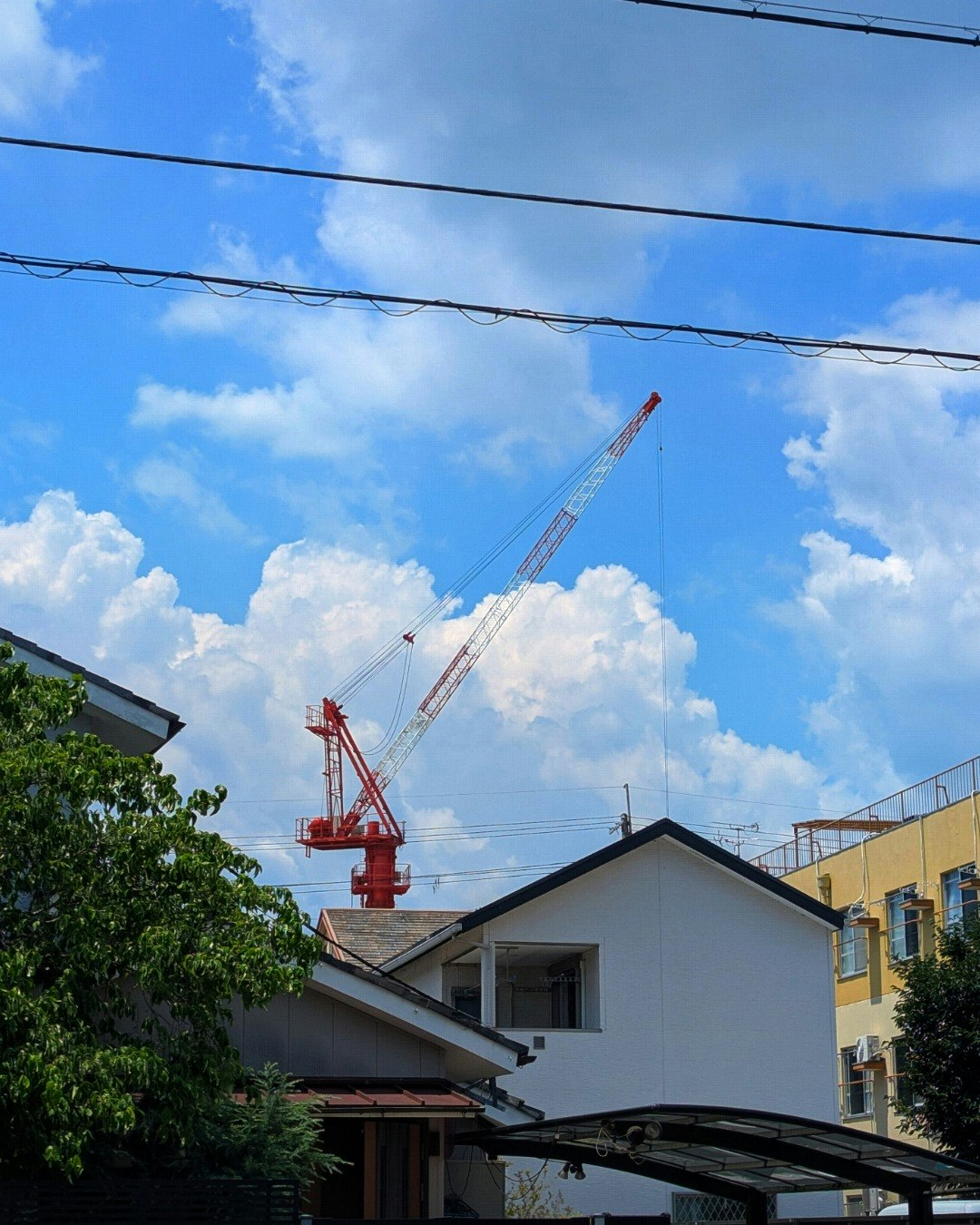 夏の青空に伸びるクレーンと雲のある建設現場