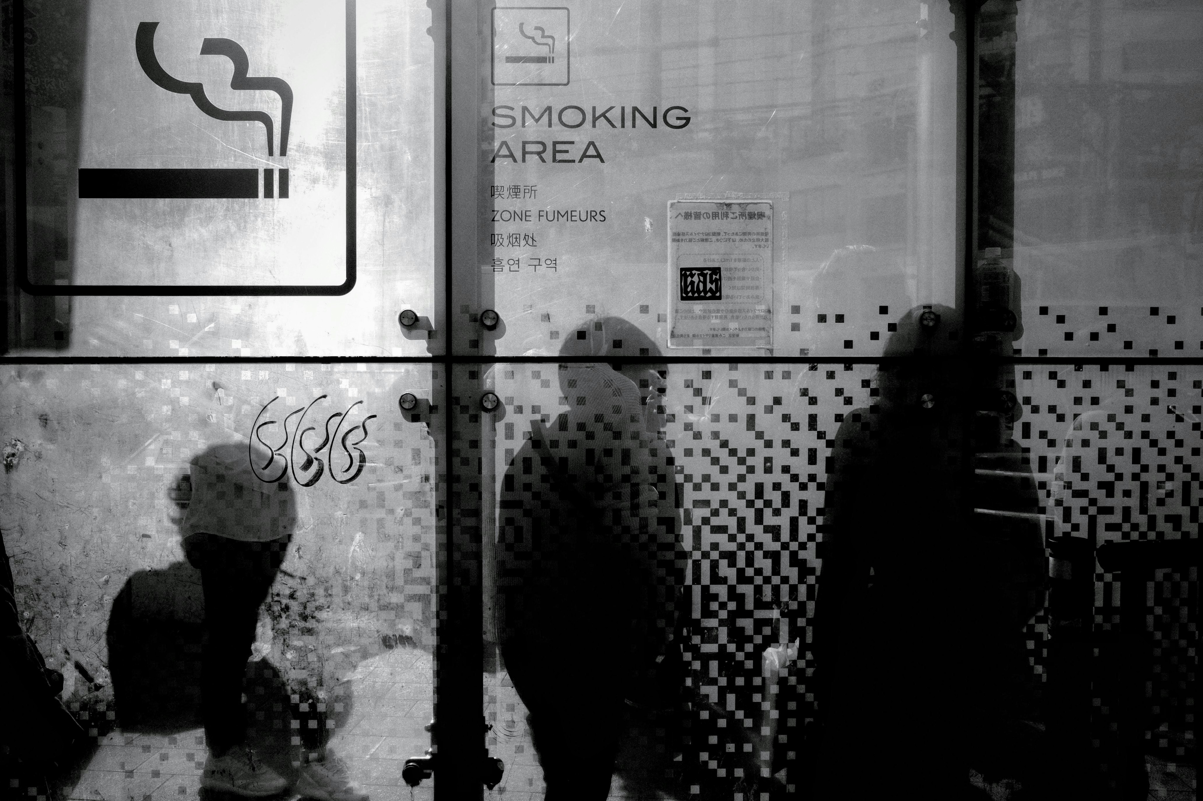 Smoking area sign on a wall and glass in an alley-like space