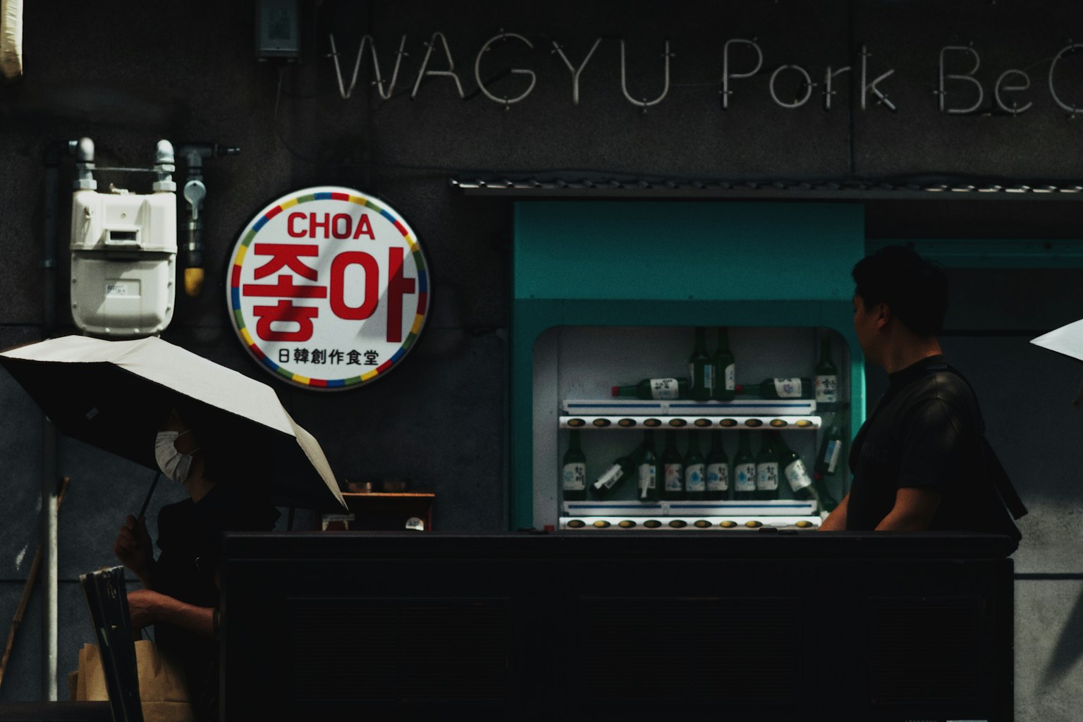 Pemandangan malam dari kios makanan dengan tanda WAGYU Pork Beef dan seorang