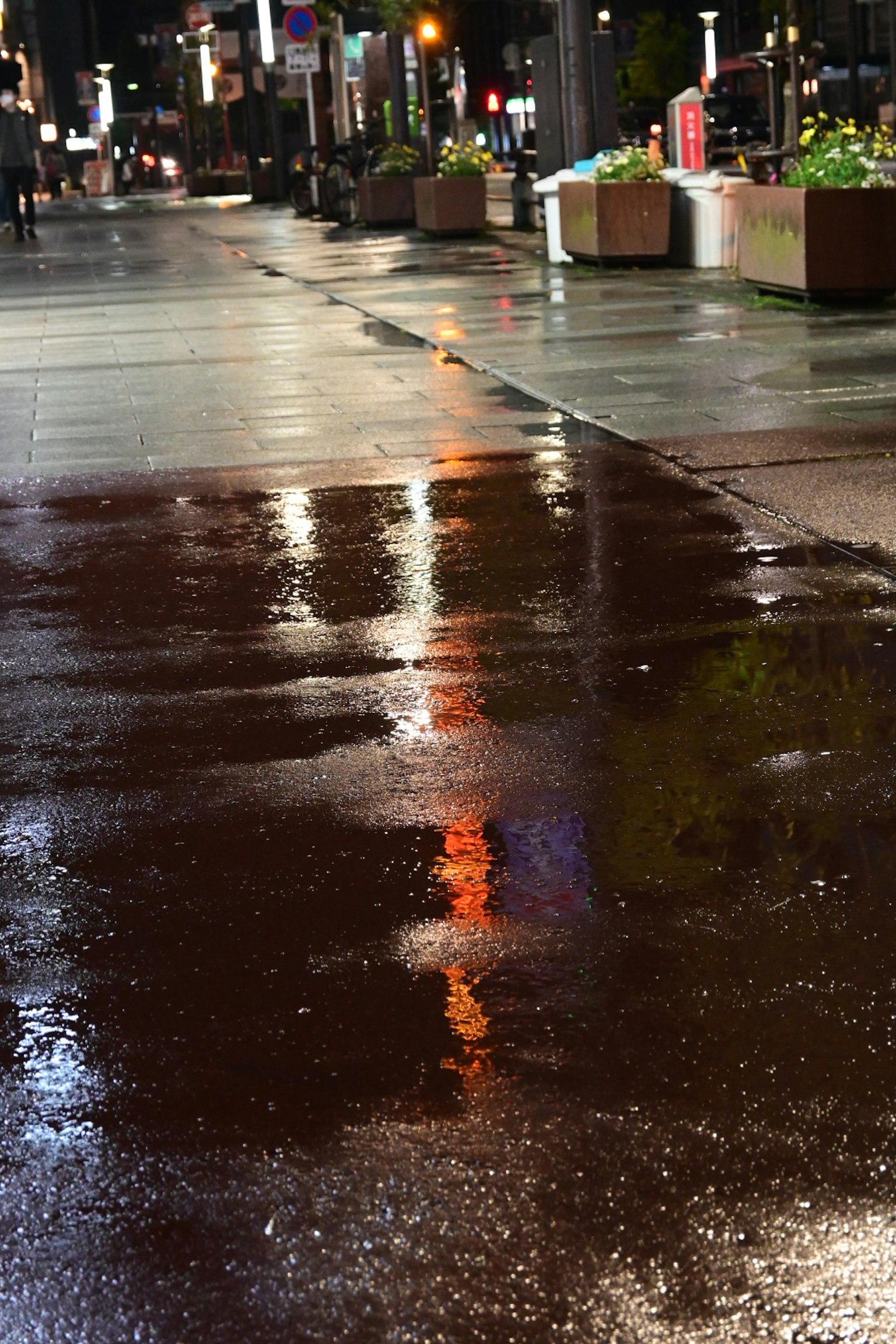 Refleksi cahaya di trotoar basah pada malam hari