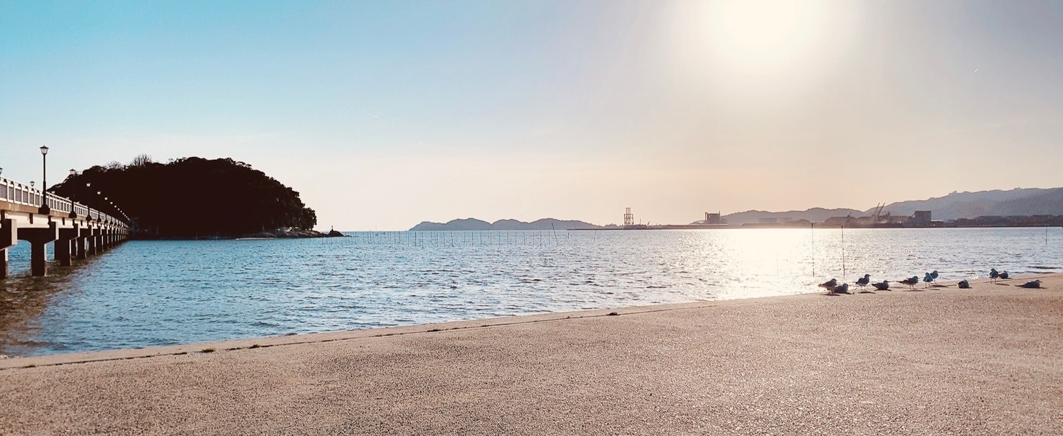 ทิวทัศน์ชายฝั่งที่มีท่าเทียบเรือและแสงแดดสะท้อนบนผิวน้ำ