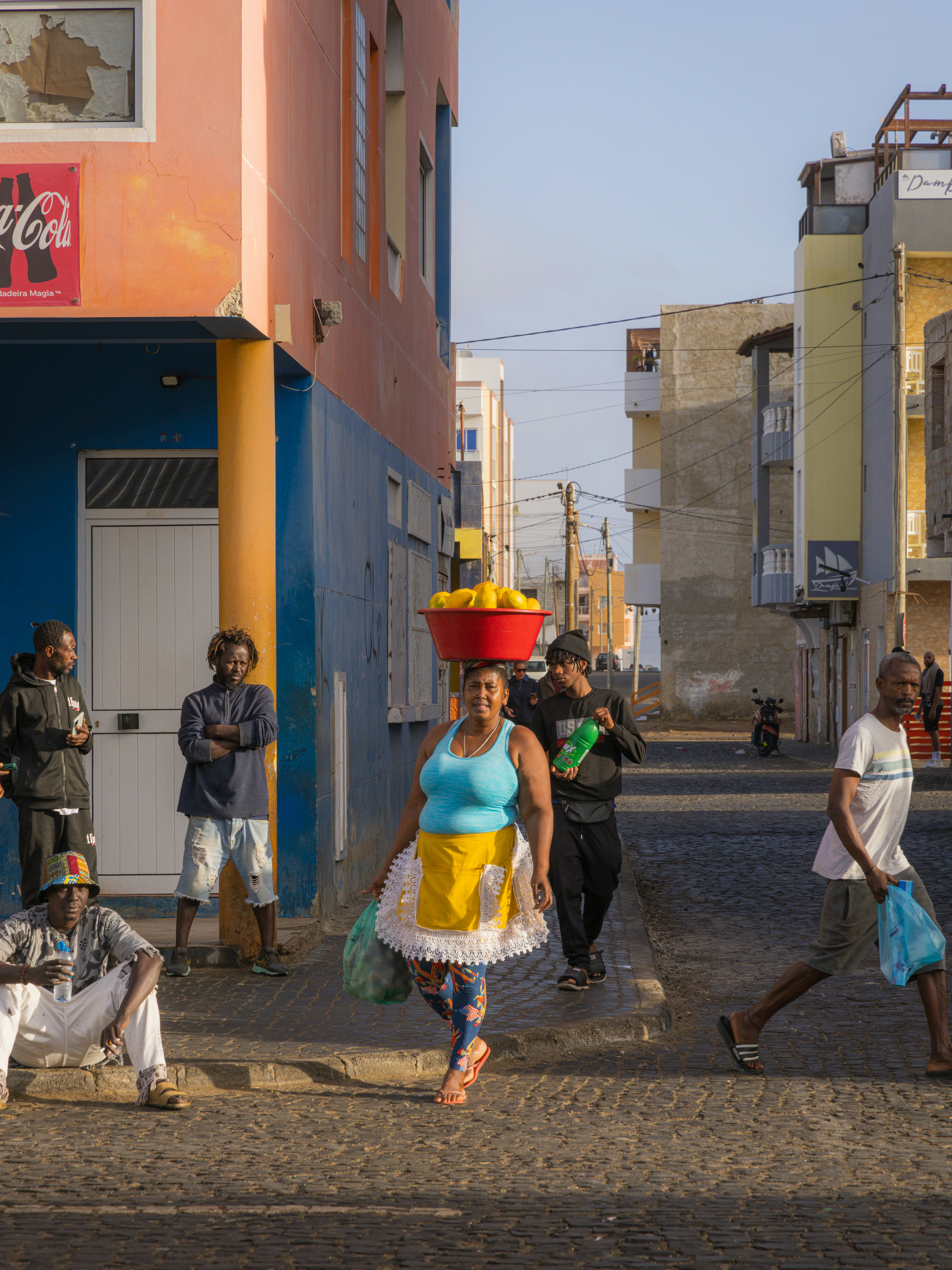 路地を歩く人々とカラフルな衣装のパフォーマーがいる街並み
