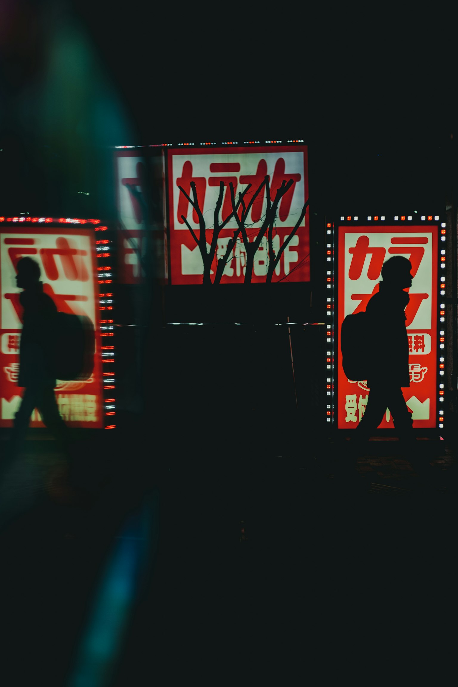 Escena urbana con letreros rojos brillantes en un fondo oscuro siluetas pasando junto a los letreros