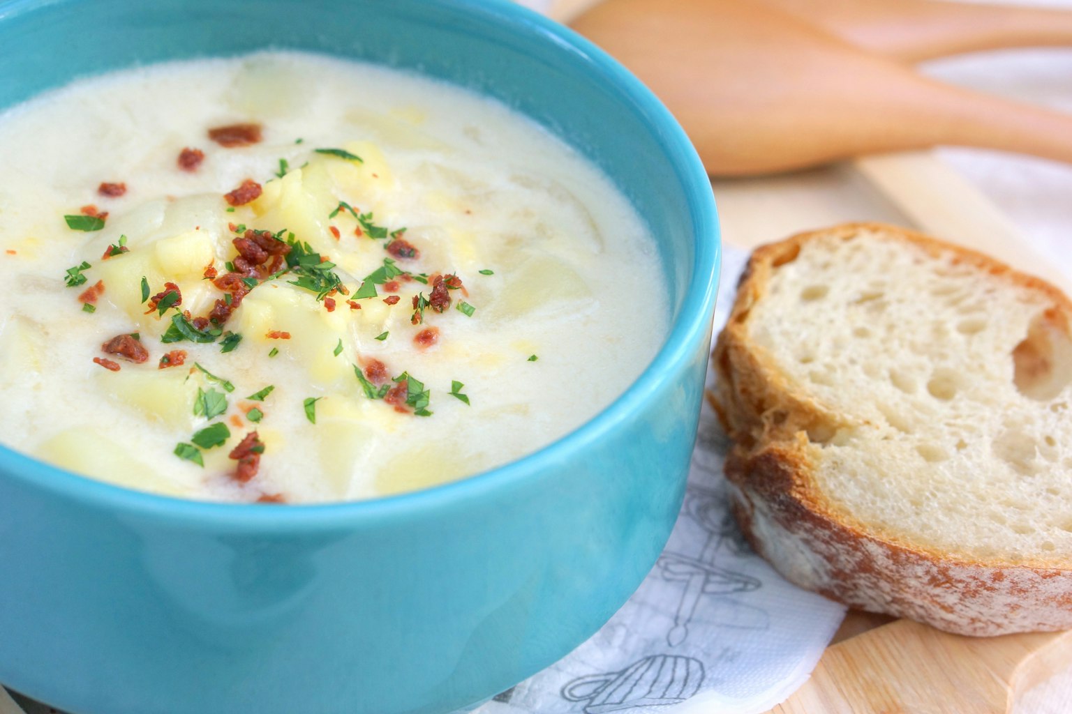Soupe crémeuse dans un bol turquoise avec du pain à côté