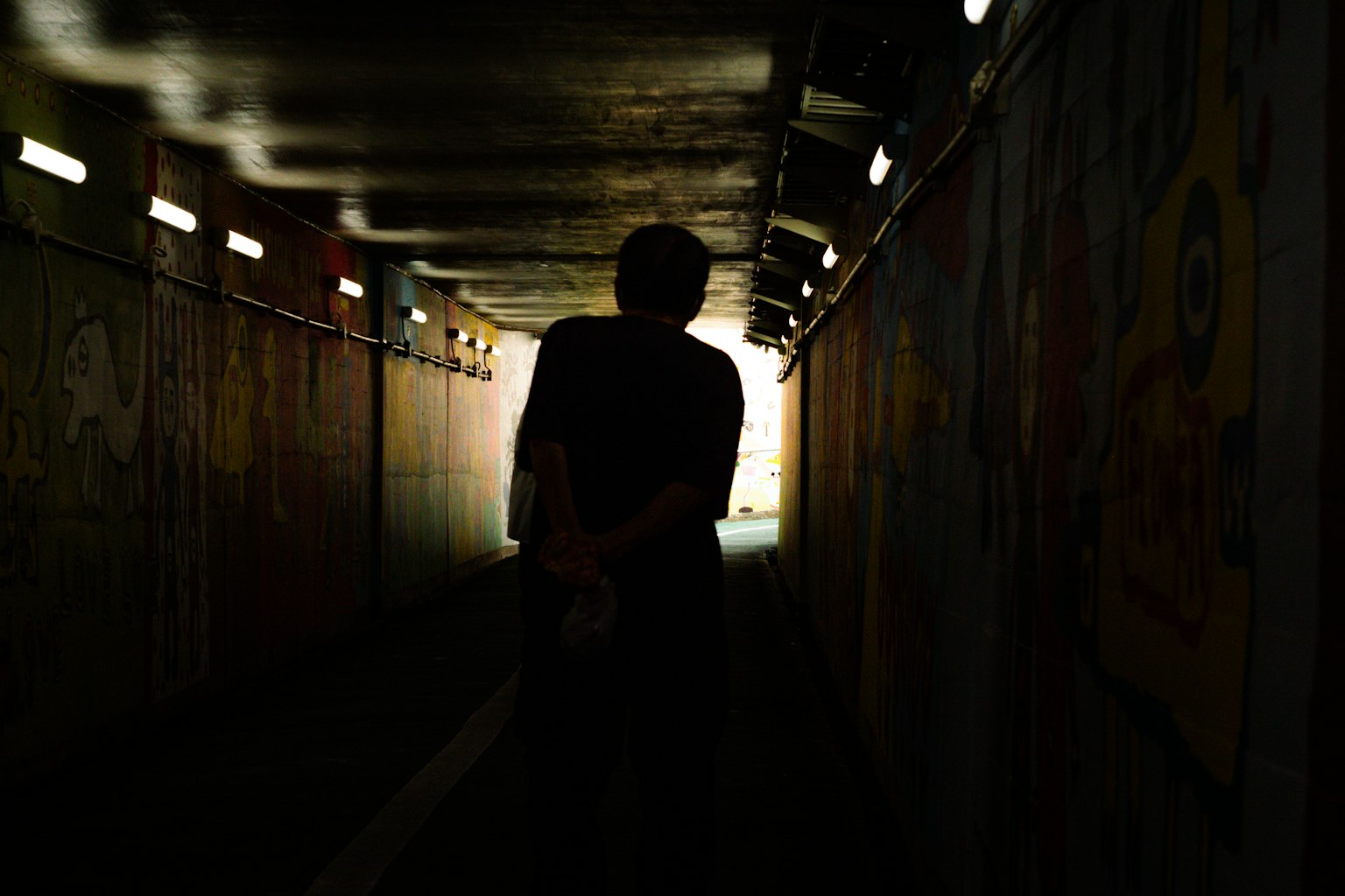 Schatten einer Person in einem dunklen Tunnel mit einem hellen Ausgang
