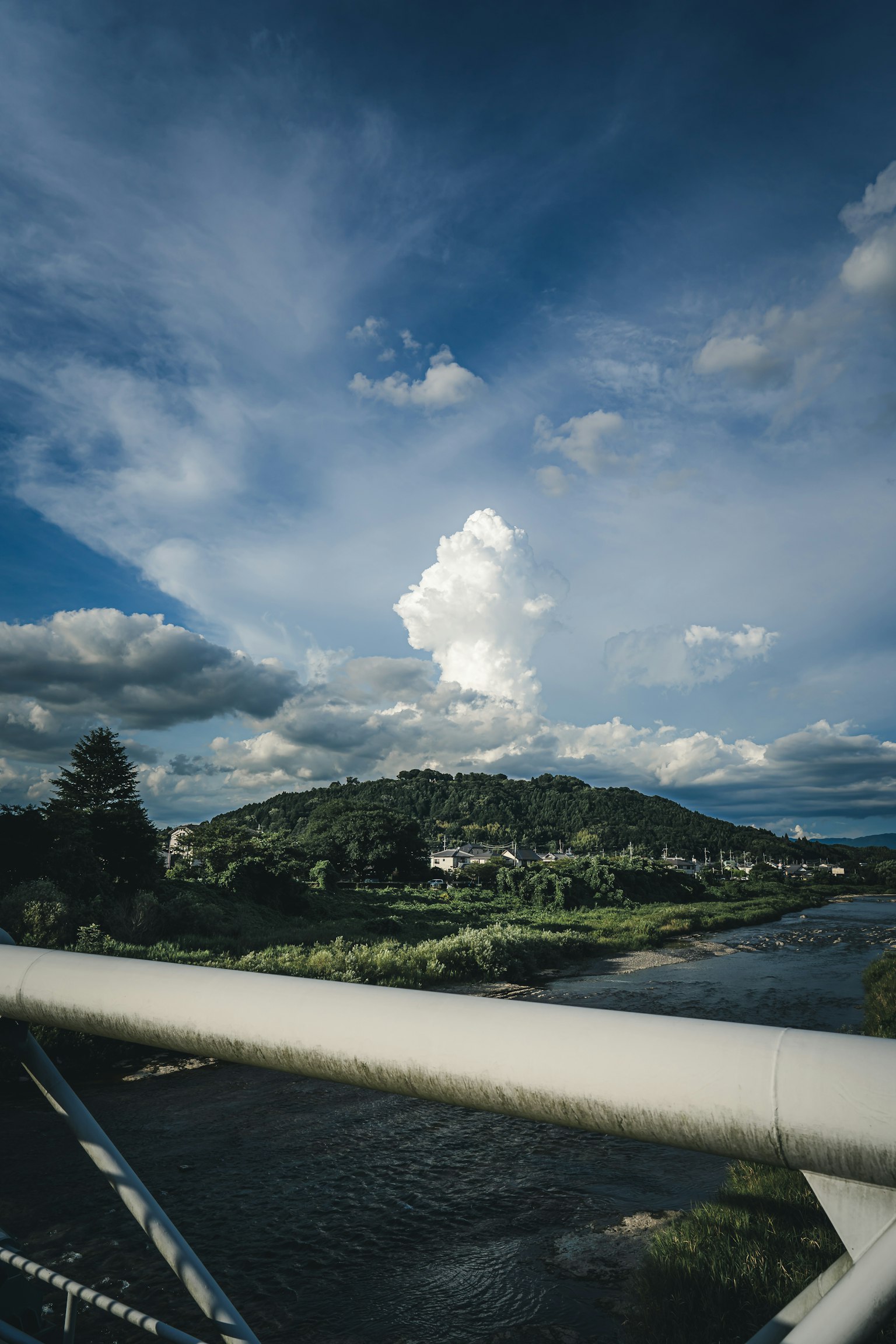 Vista escénica desde un puente con colinas verdes y un río bajo un cielo azul