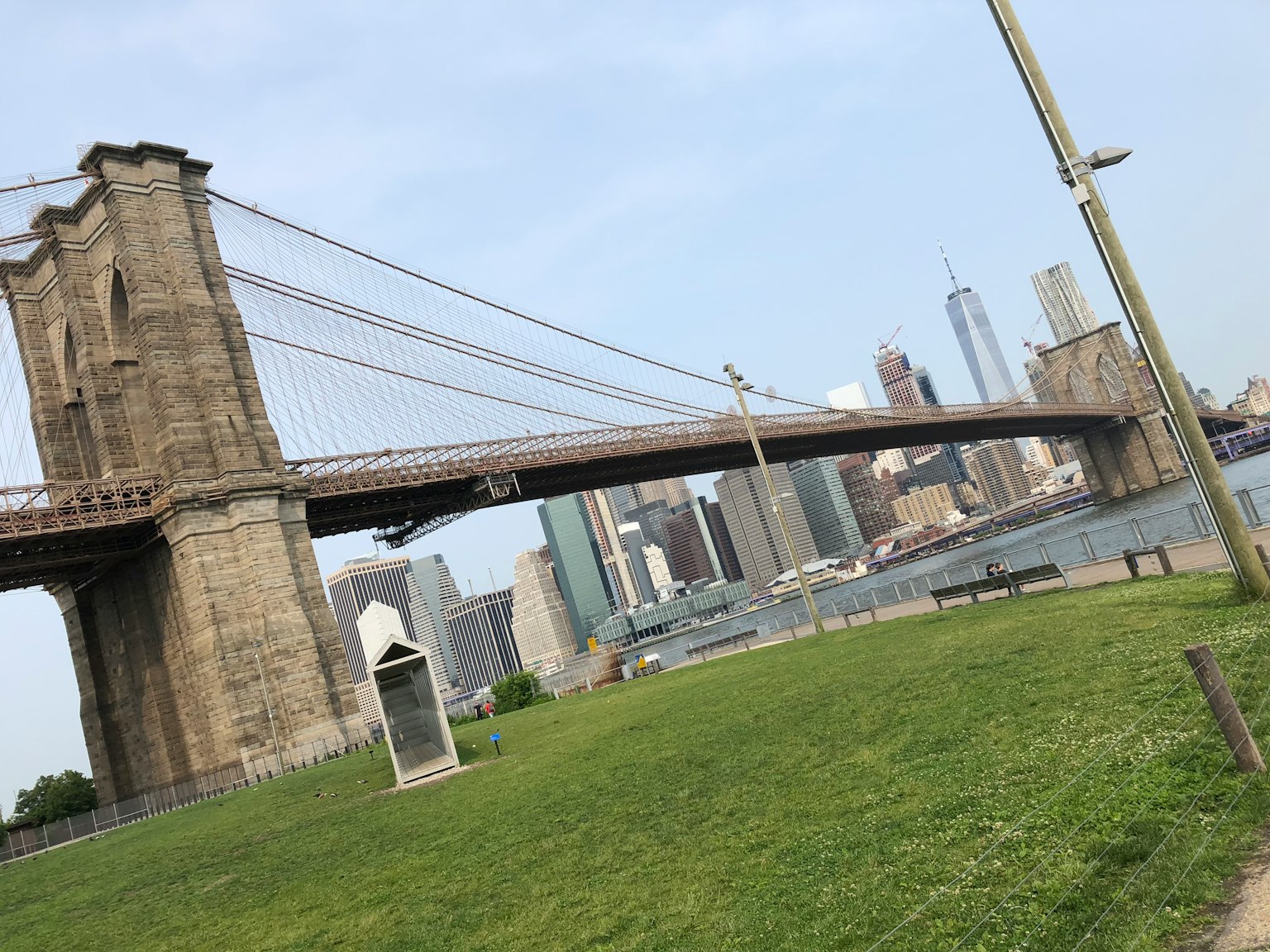 Pont de Brooklyn avec la ligne d'horizon de New York en arrière-plan et un parc verdoyant au premier plan