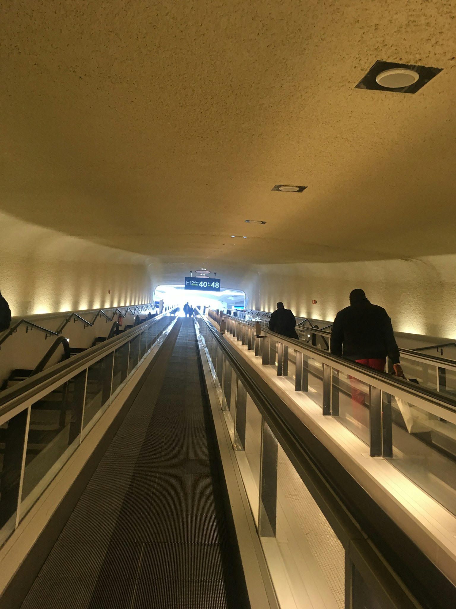 Long escalator tunnel leading to a bright exit