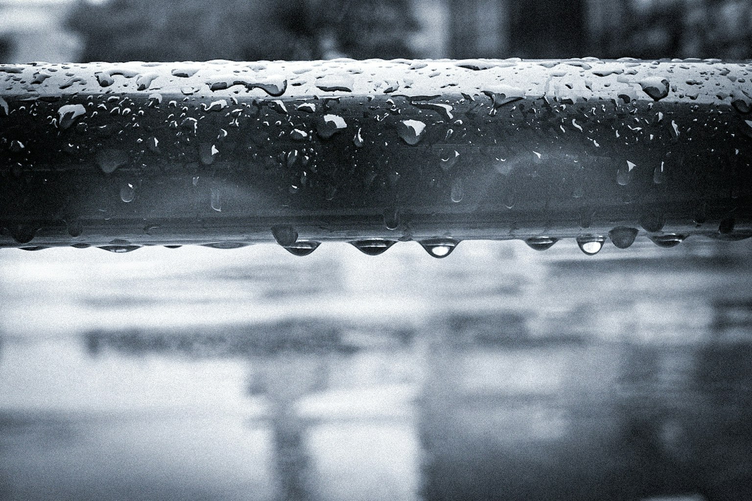 雨滴がついた金属の手すりとぼやけた背景