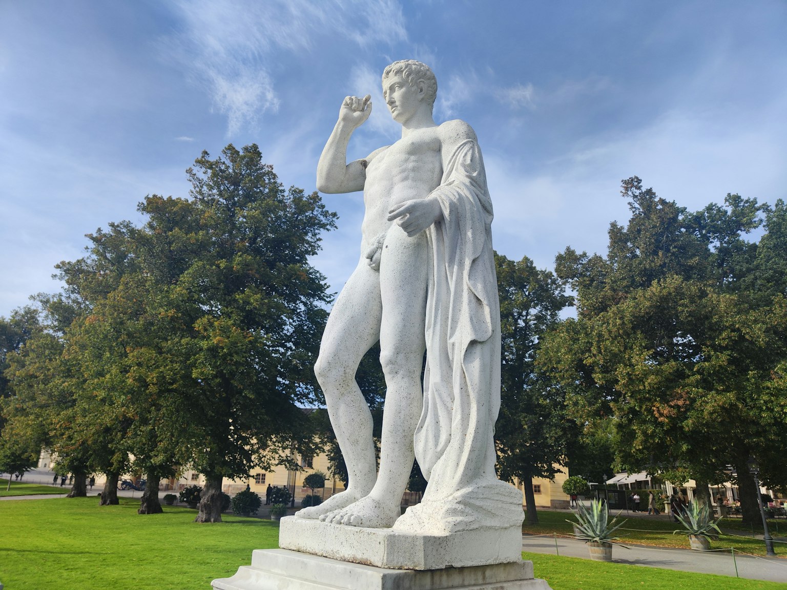 Estatua de mármol blanco de una figura de pie en un parque