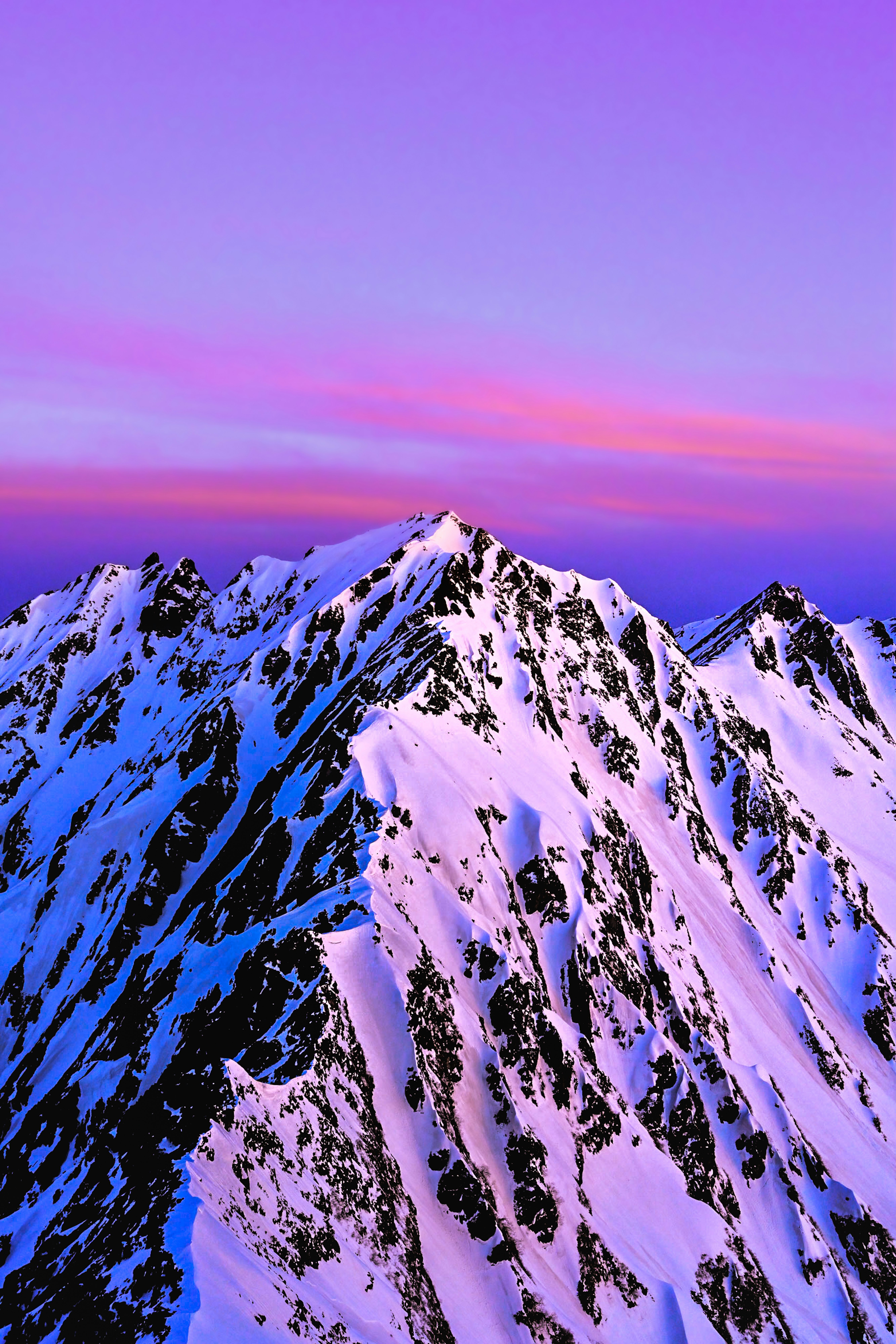 夕焼けの空と雪山の稜線が広がる山岳風景