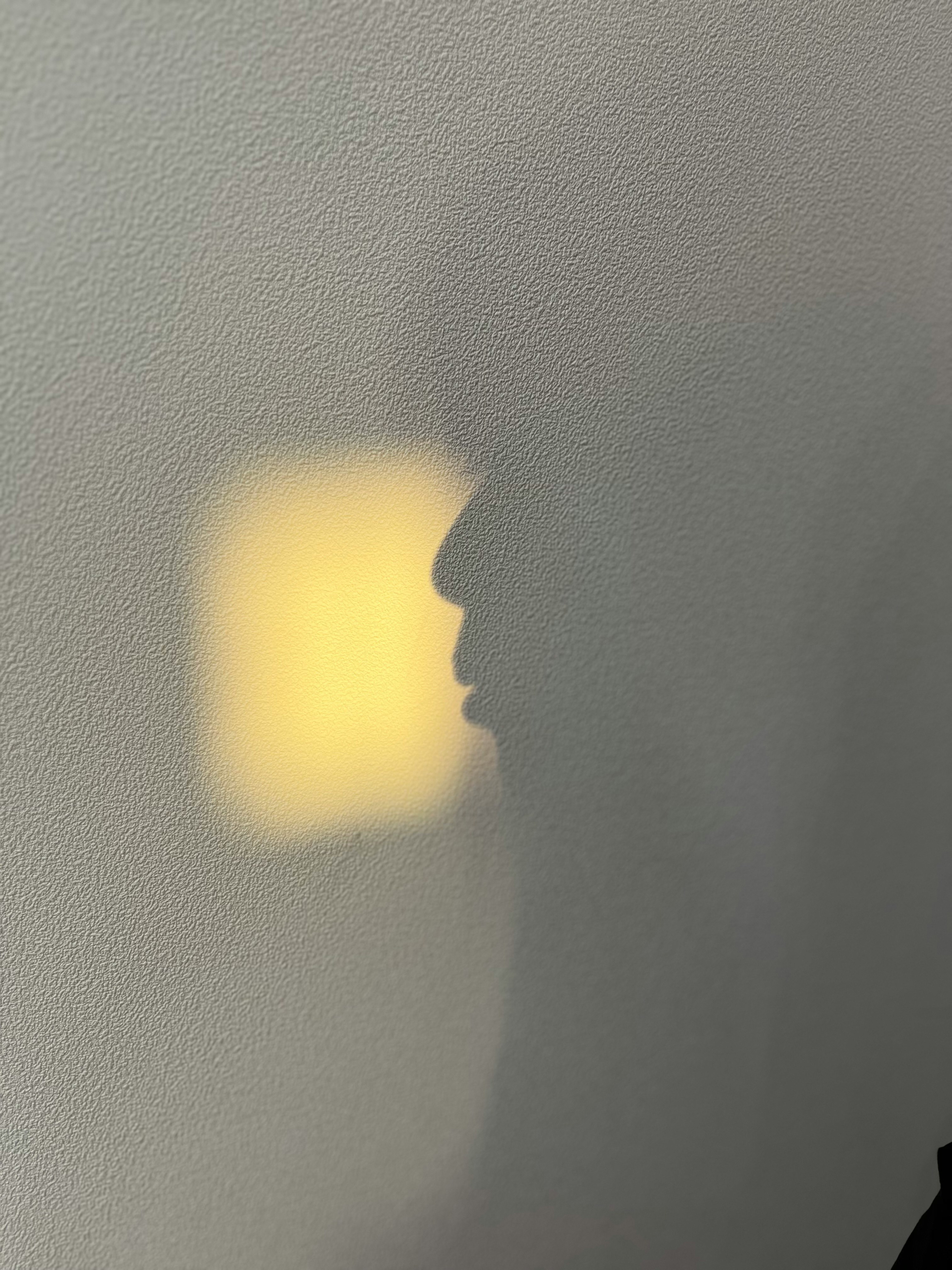 影の中に浮かぶ人の横顔と黄色い光の四角
